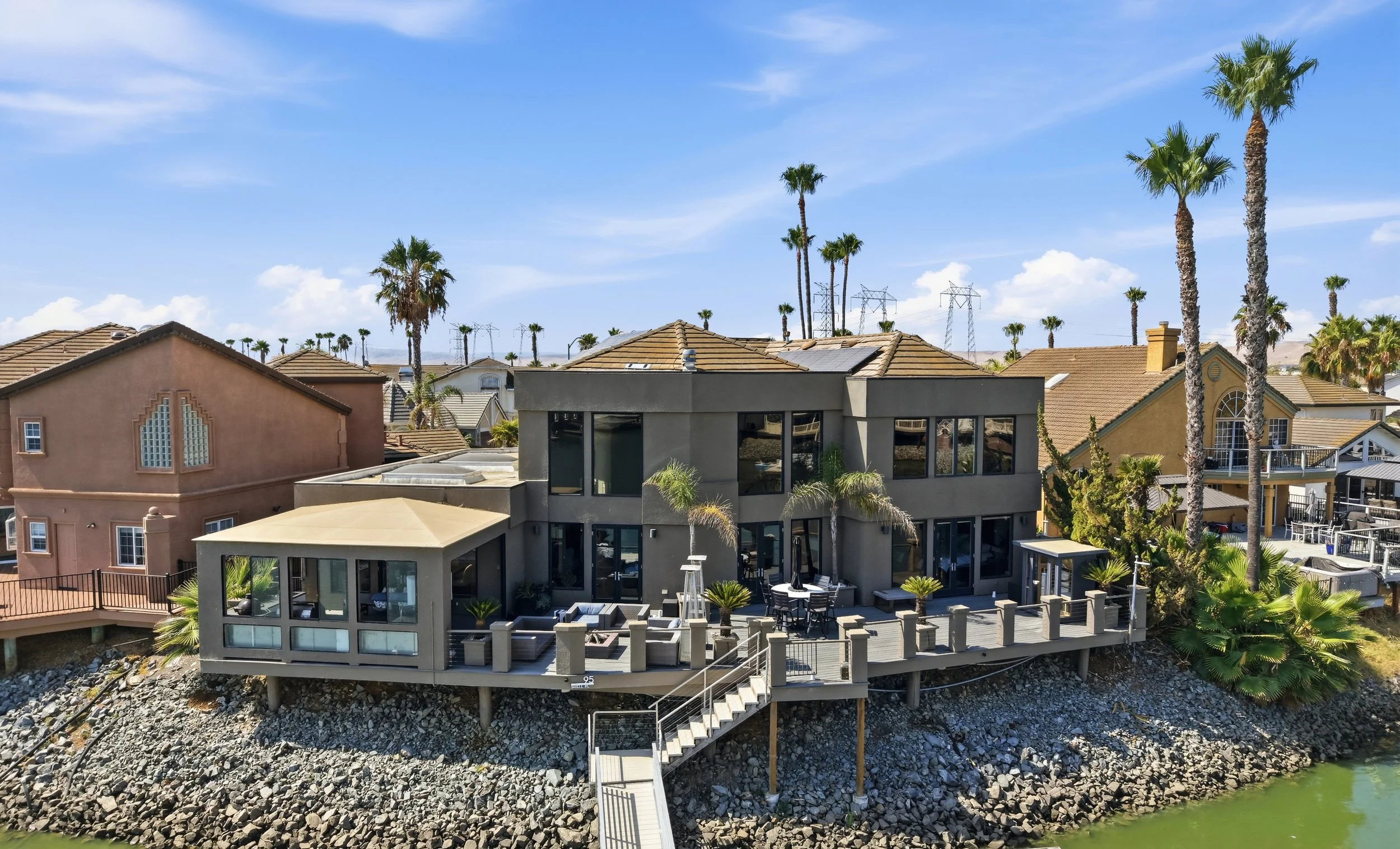 Aerial view of modern houses with palm trees in a sunny suburban neighborhood.
