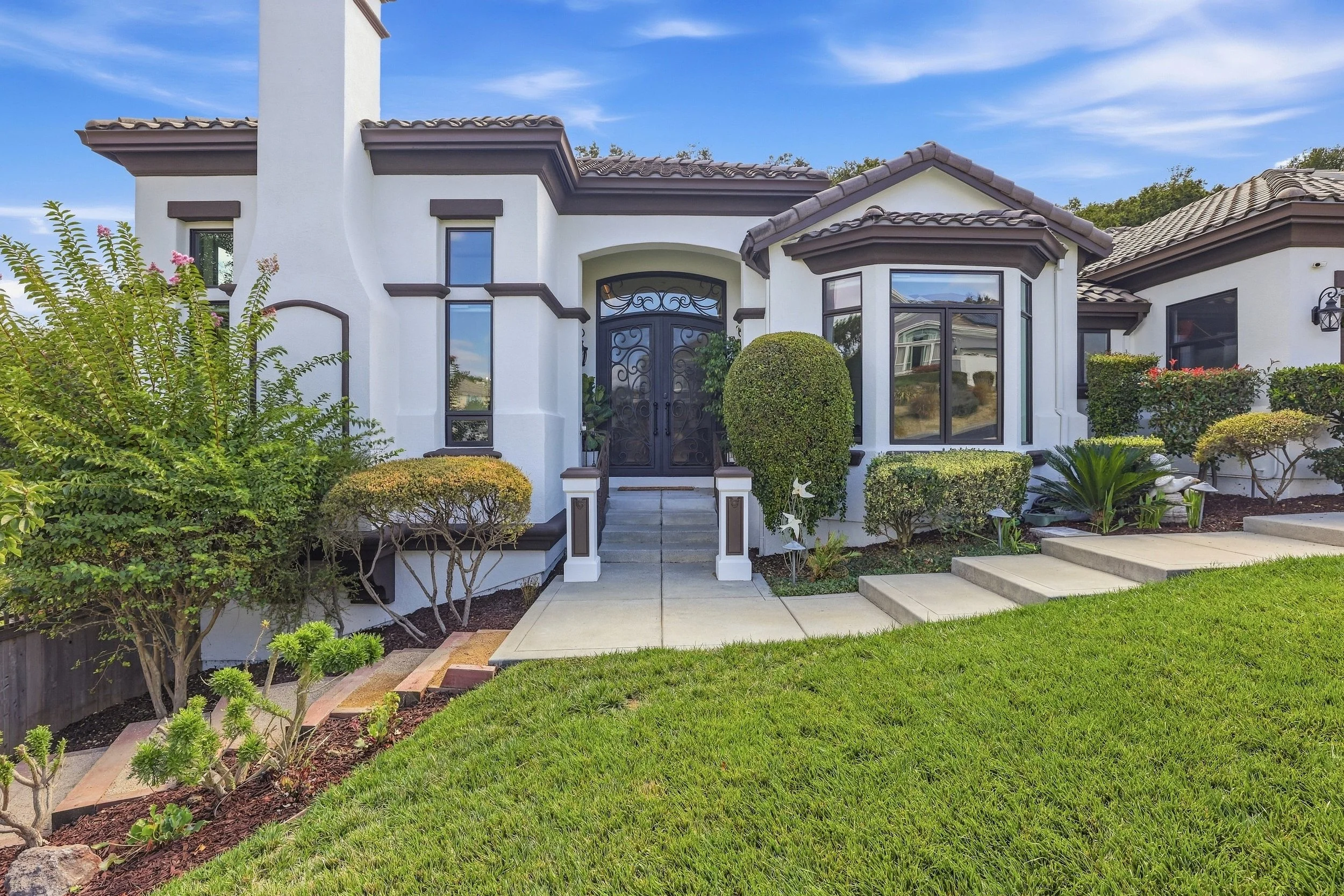 Front entrance of a stucco home with decorative columns and a green lawn.