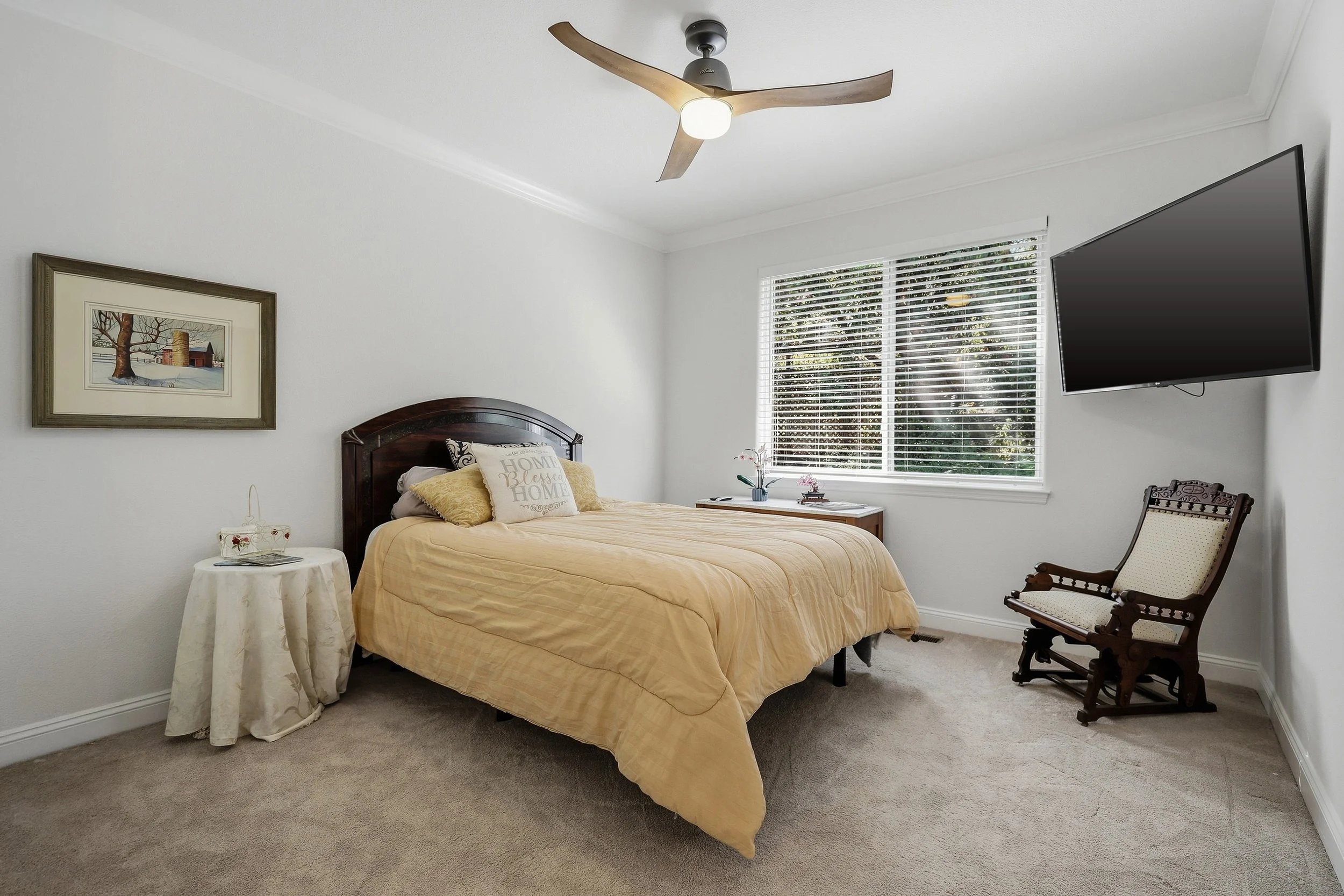Bedroom with yellow bedding, ceiling fan, and garden views.
