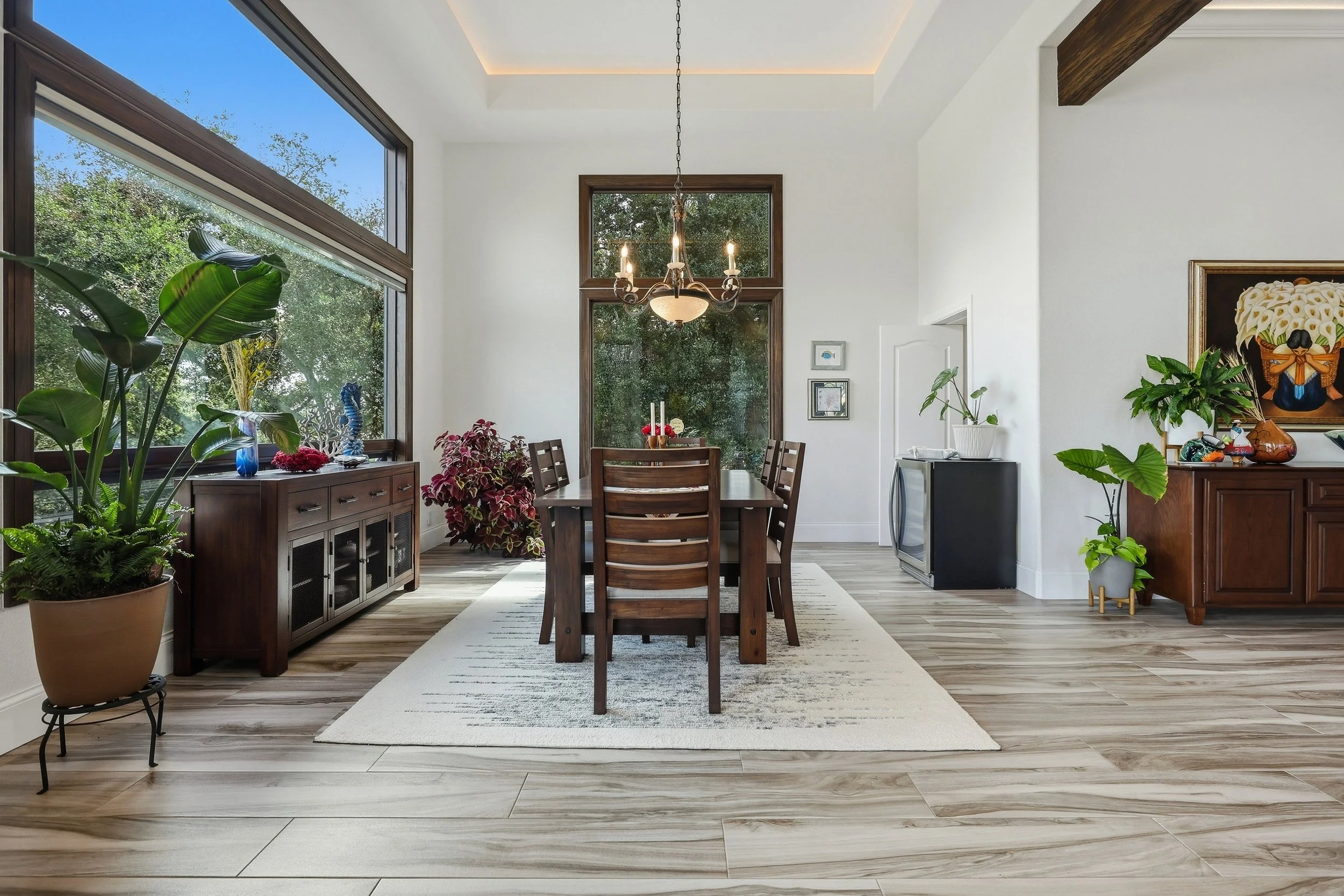 Dining room opening to a bright living area with high ceilings.