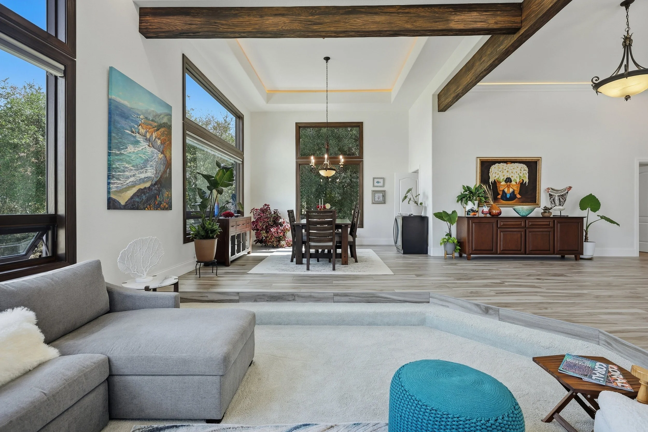 Open living and dining area with exposed ceiling beams and wood flooring.
