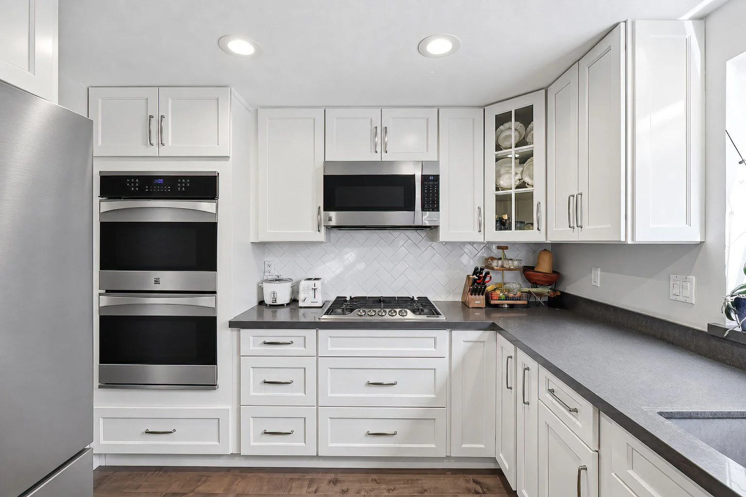 White kitchen cabinetry with stainless-steel appliances and black countertops.