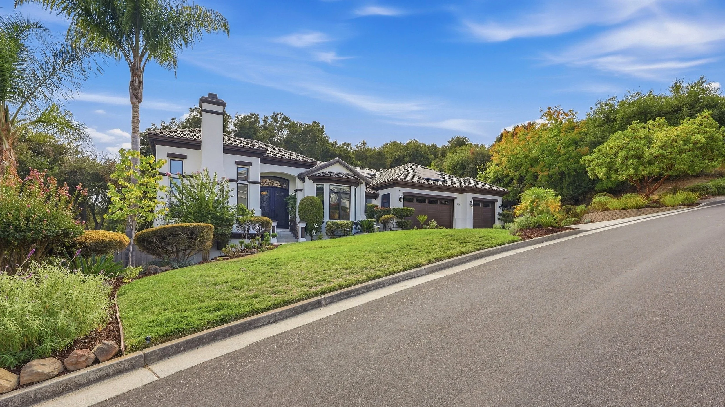 Street view of a Gilroy home with mature landscaping and garage.