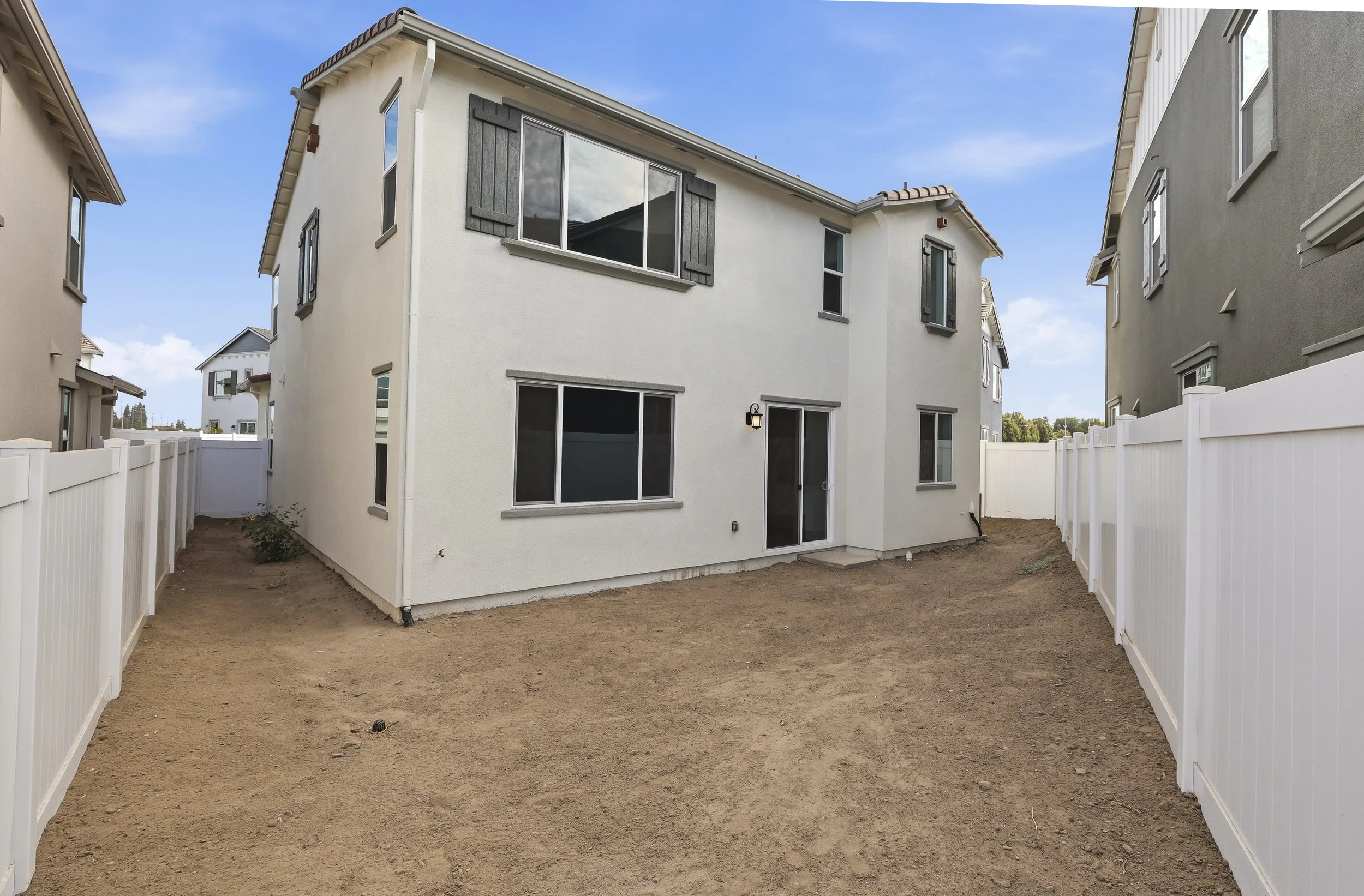 Rear exterior of a two-story home with an unfinished backyard.