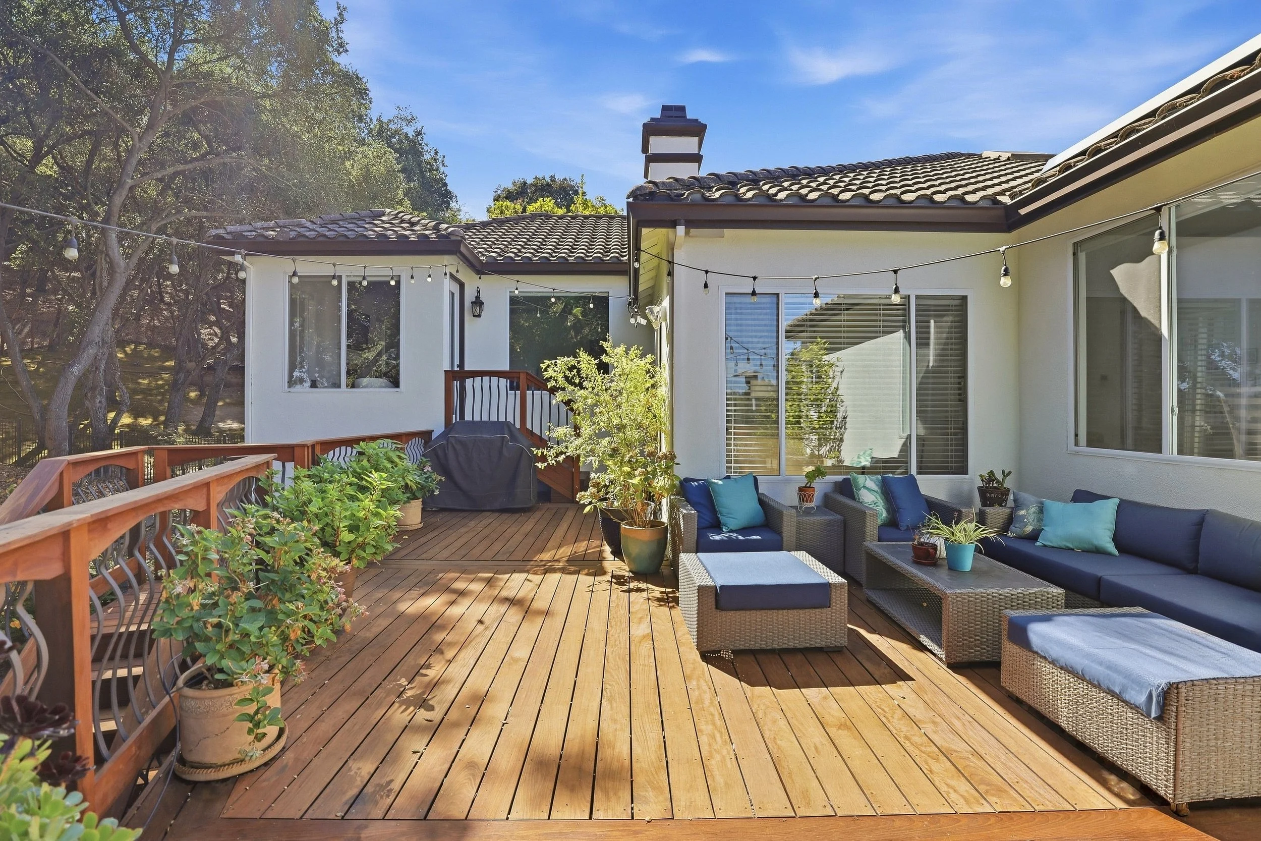 Wood deck with outdoor lounge chairs beside a stucco home.