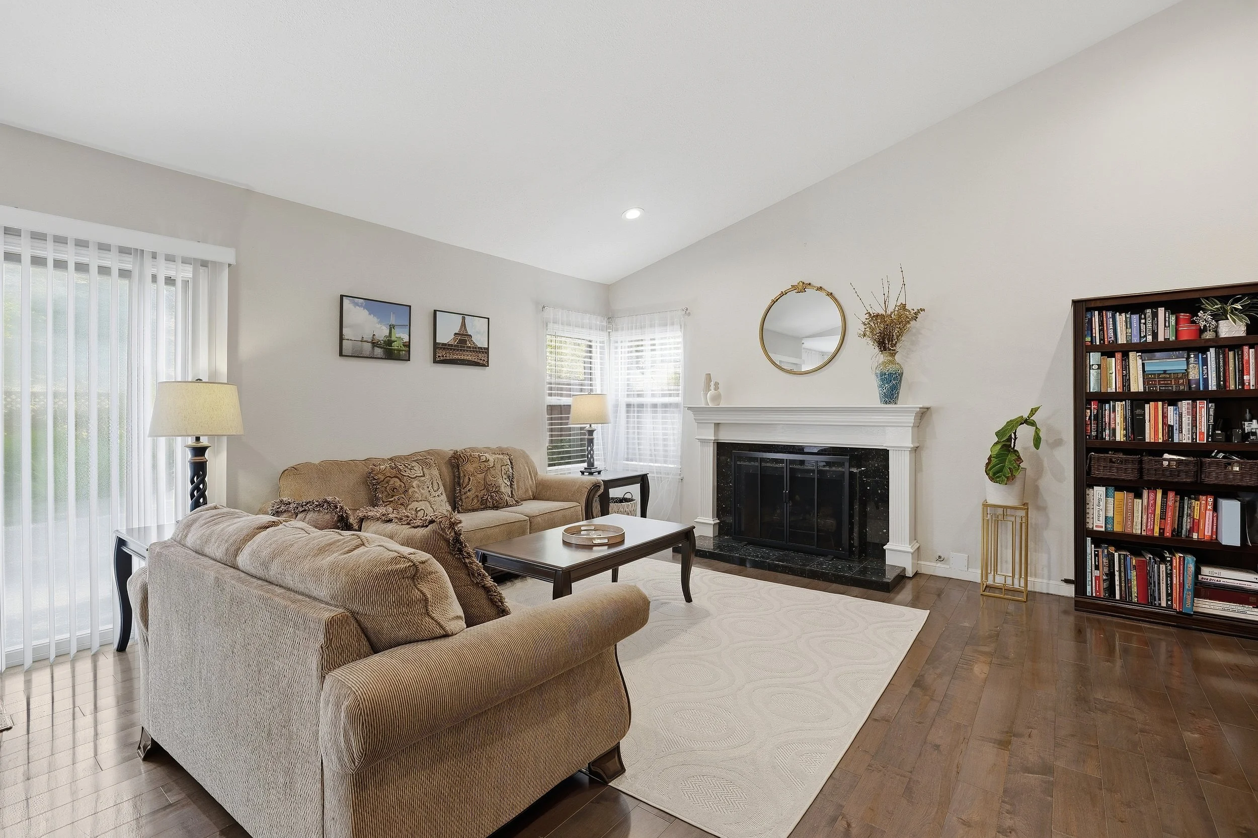 Living room with sofa, fireplace, television, and wood flooring.