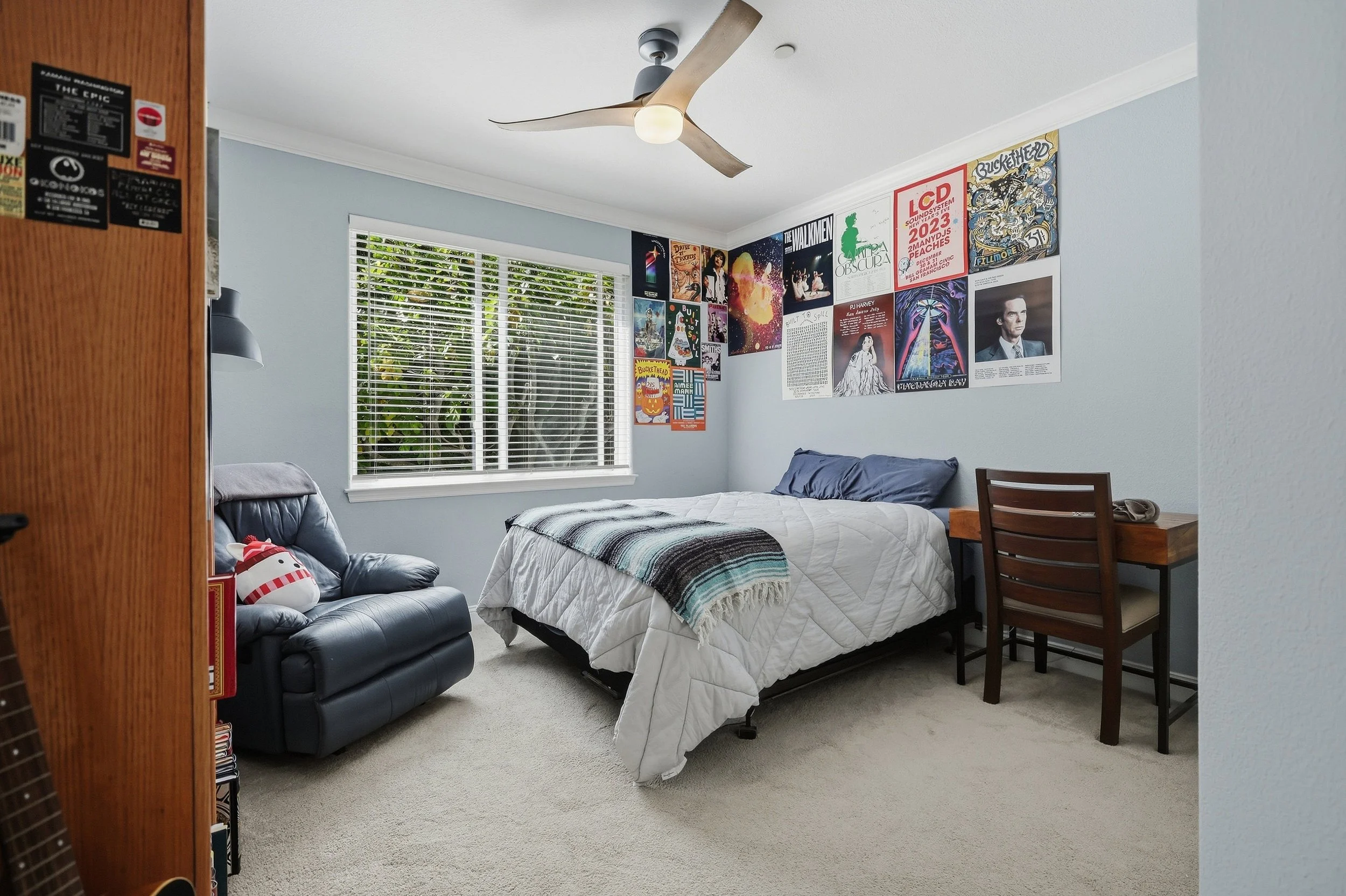Bedroom with patterned bedding, ceiling fan, and large windows.