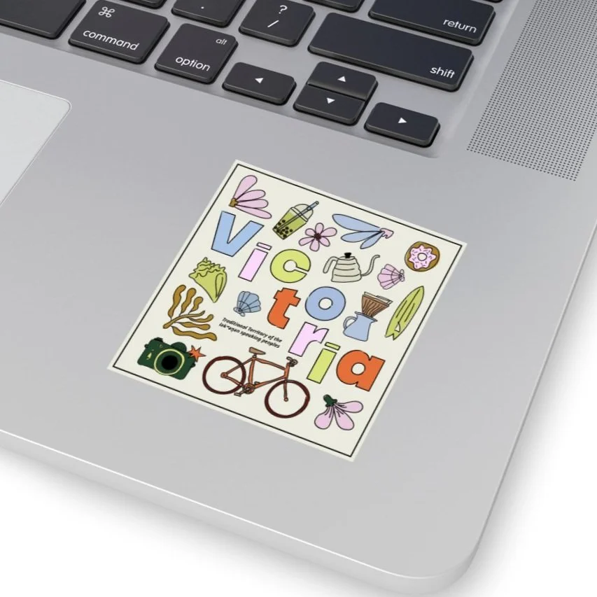 Colorful sticker with illustration of various objects and the word "Victoria" on a silver laptop keyboard.