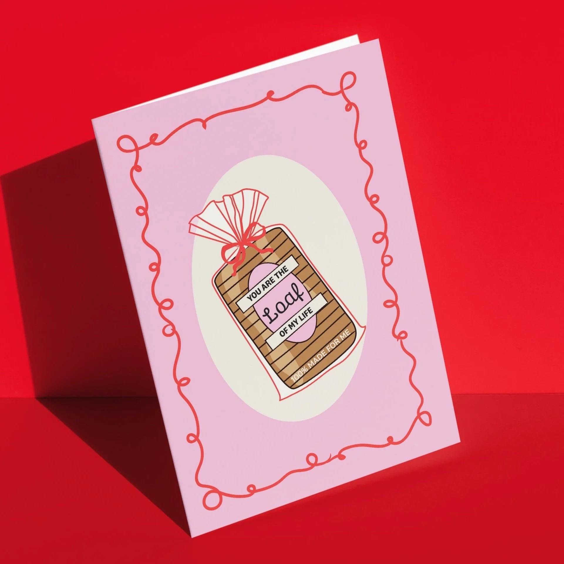 Pink greeting card with a red decorative border, featuring a drawing of a gift box with a pink ribbon and a tag that reads "You are the glue of my life" and "100% made for me."