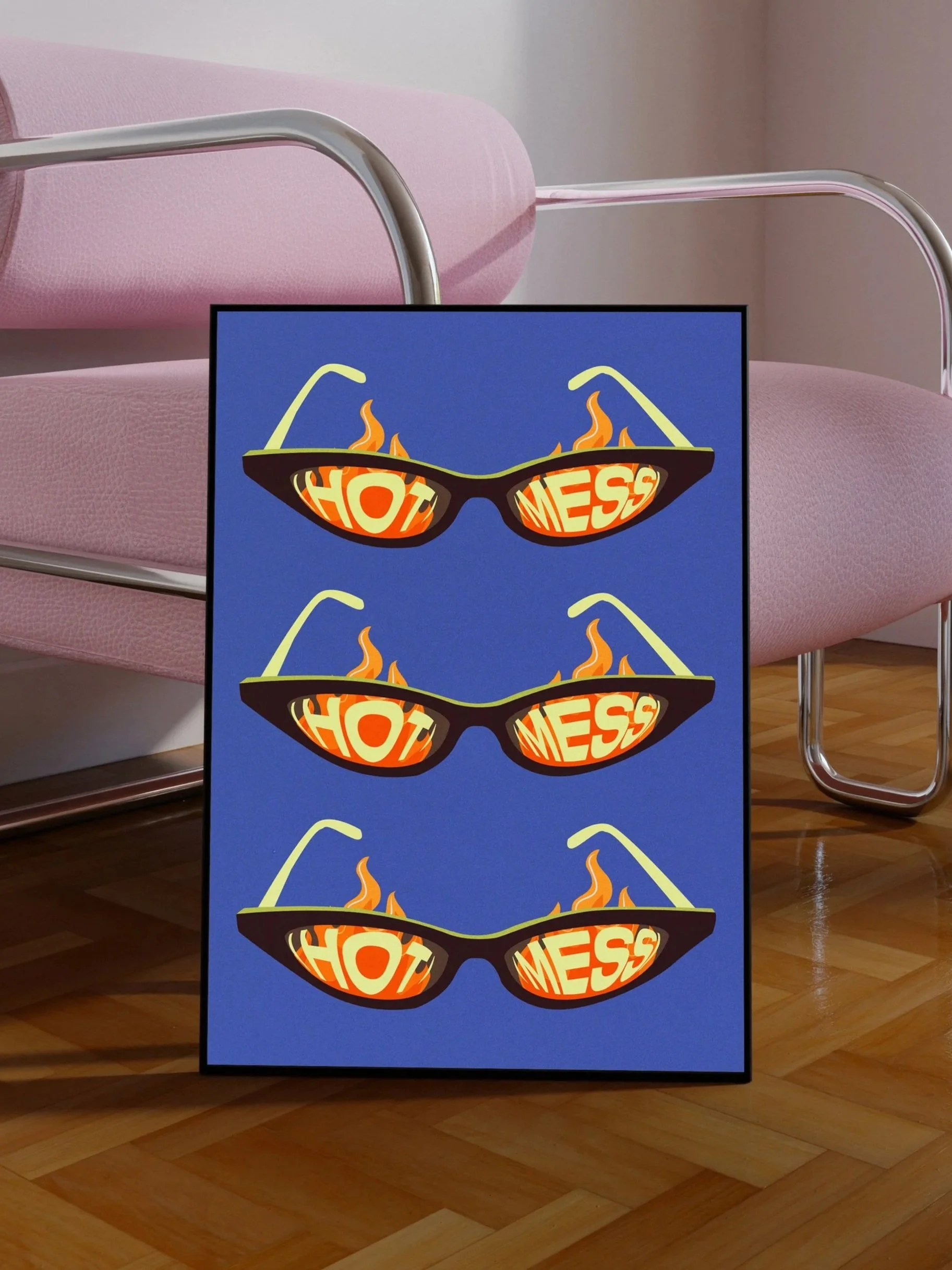A signboard with three pairs of sunglasses graphic, each with the word "HOT" on the left lens and "MESS" on the right lens, with flames in the lenses, set against a blue background, in front of a pink chair.