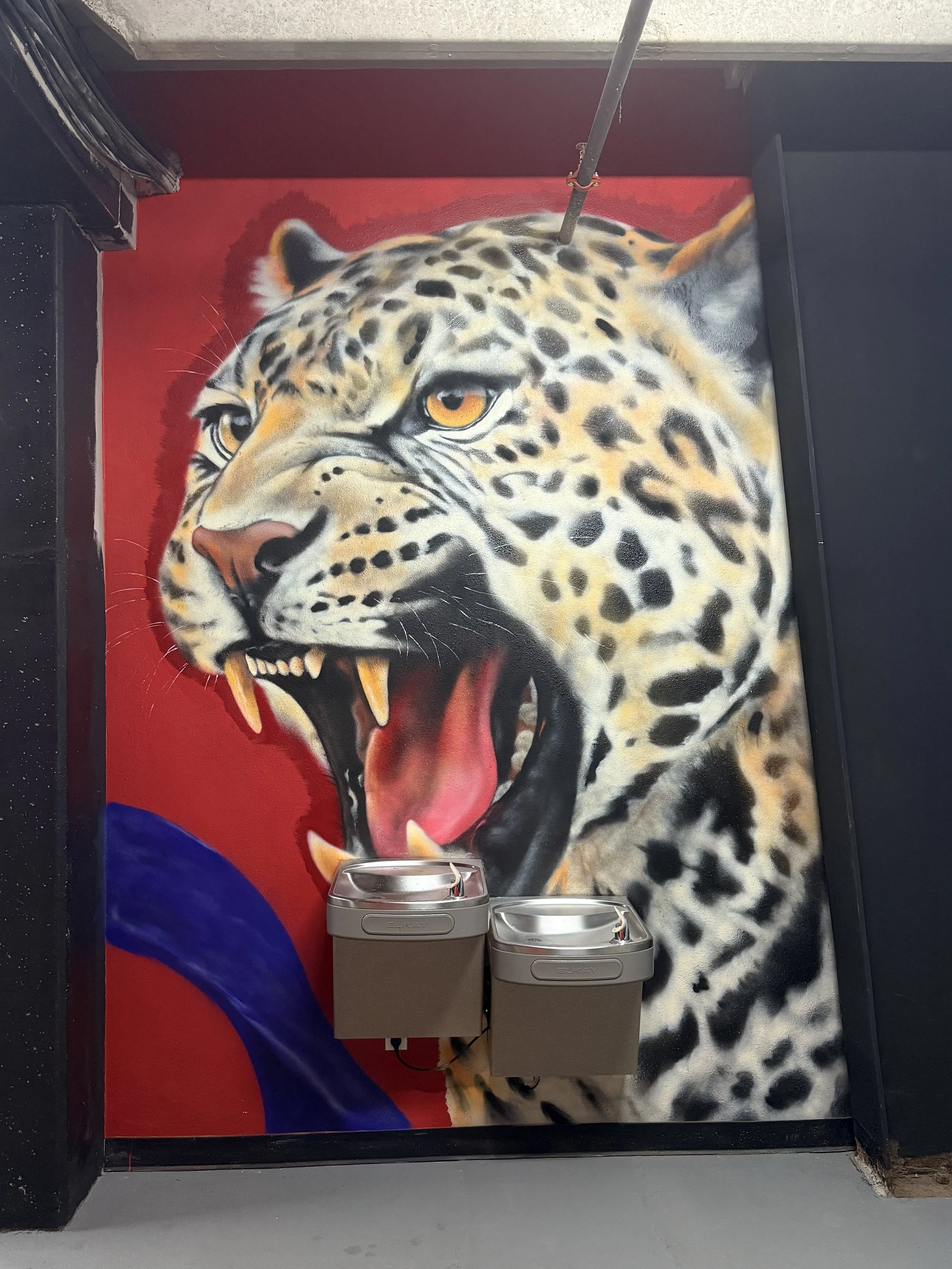 A fierce jaguar brings strength and intensity into Combat Warriors. In Mexica culture, the jaguar was associated with power and warfare and became an important symbol among elite warriors. I worked the composition around the existing water fountains,