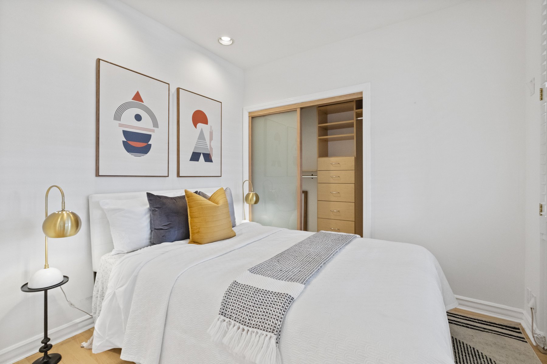 Real estate picture showing a bedroom with a white bed and lamp nearby.