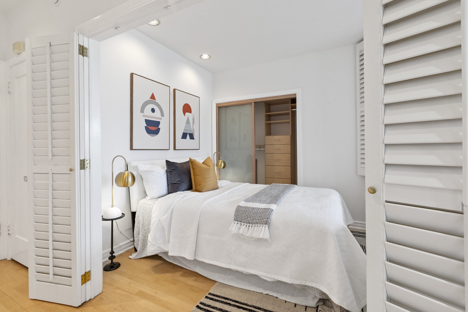 Real estate picture showing a bedroom, closet, and entrance to the room.