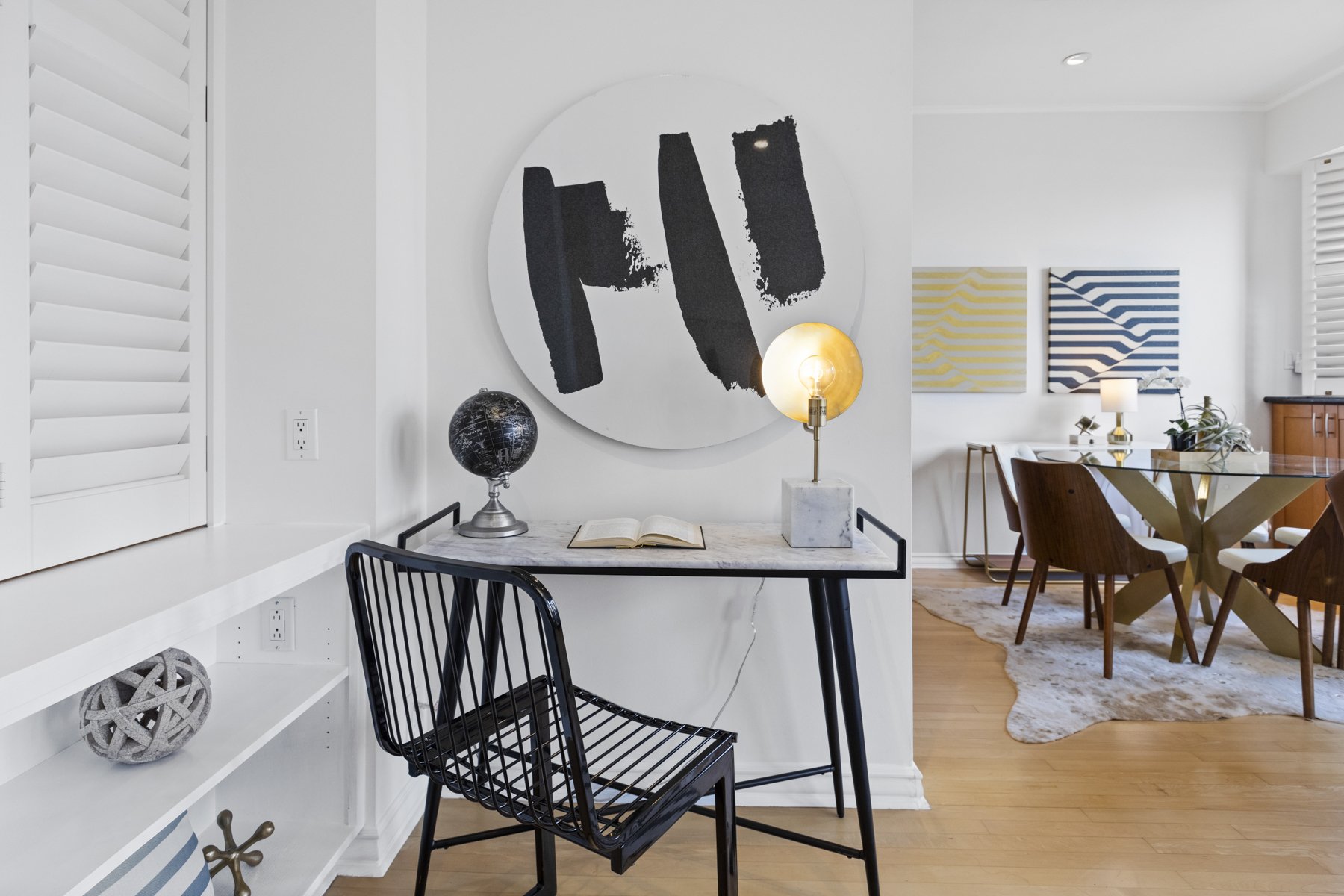 Real estate photography picture showing a desk, painting, and a little bit of a living room.