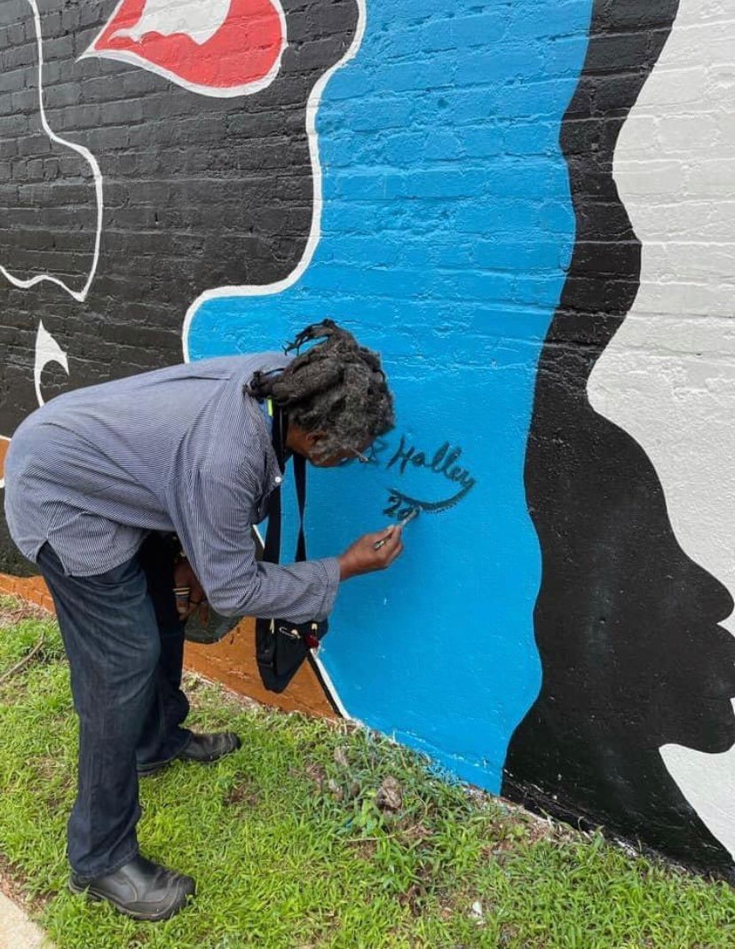 Lonnie Holley signing his mural titled "Born into Colors" and "Black in the Midst of the Red, White and Blue" (2021)