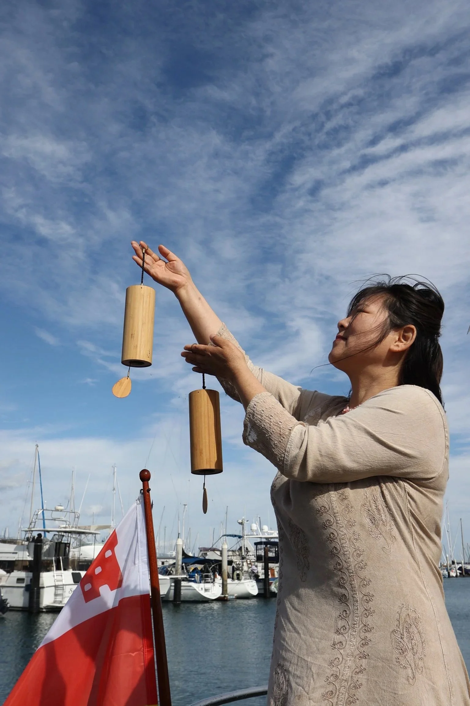 Sound Practitioner playing hanging chimes aboard yacht Kelpie during a private Sound Bath Sail in Santa Barbara.