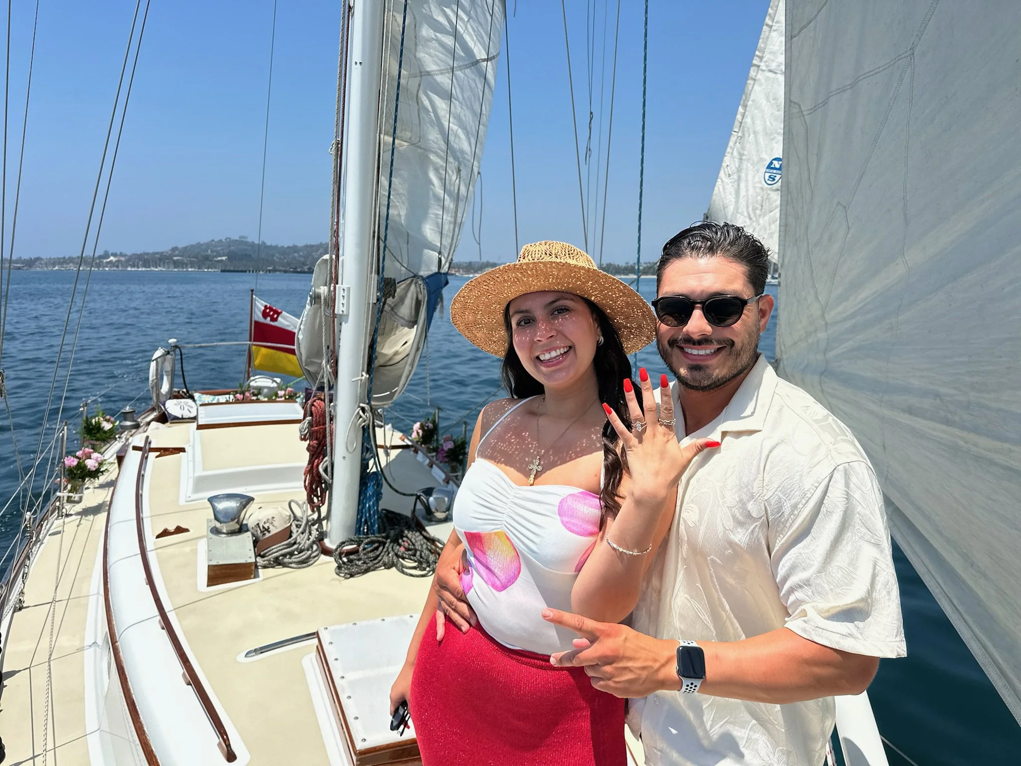 Couple smiling aboard Yacht Kelpie while showing their engagement ring after their proposal.