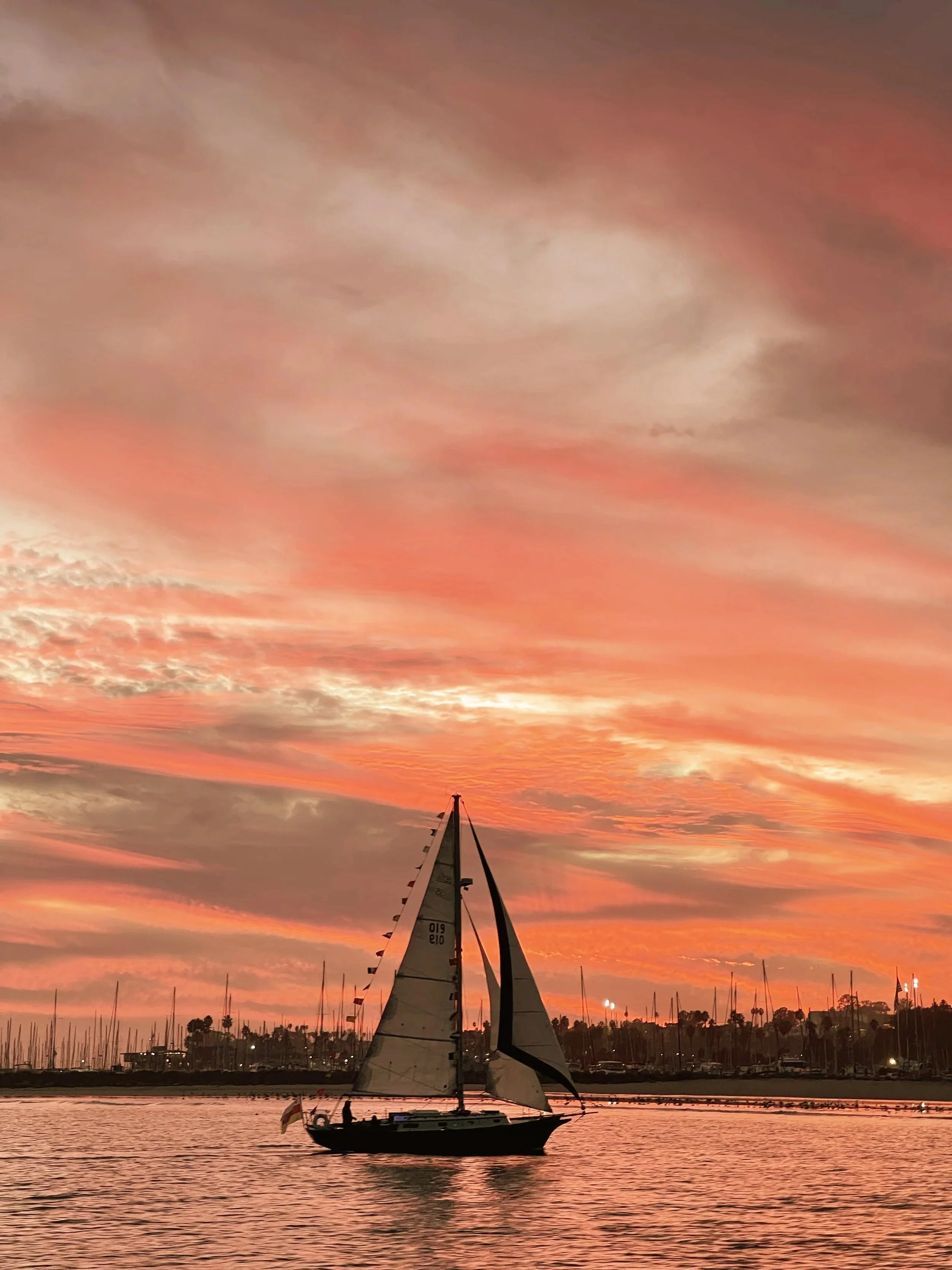 Sailboat near Santa Barbara Harbor beneath a vivid pink sunset sky