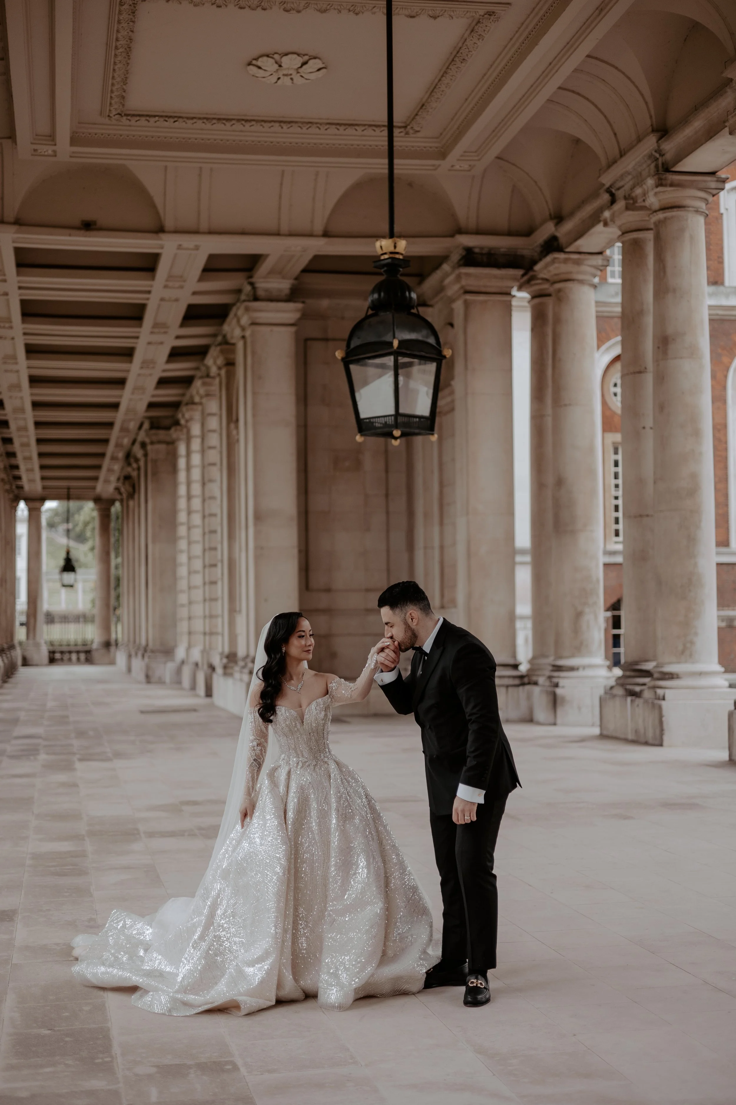 Bride holding embellished wedding dress, wearing veil and jewelry.