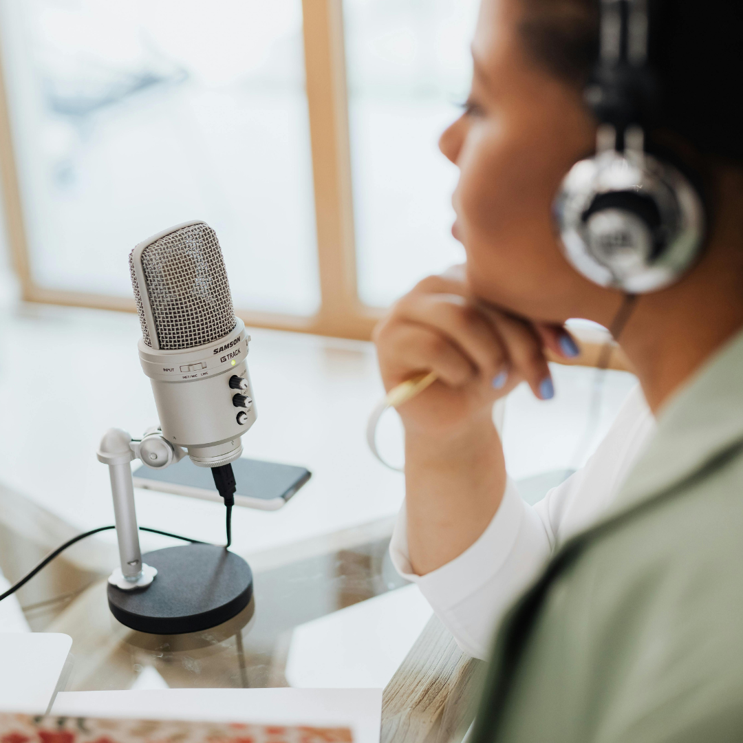 woman wearing a headset sitting in front of a podcast mic
