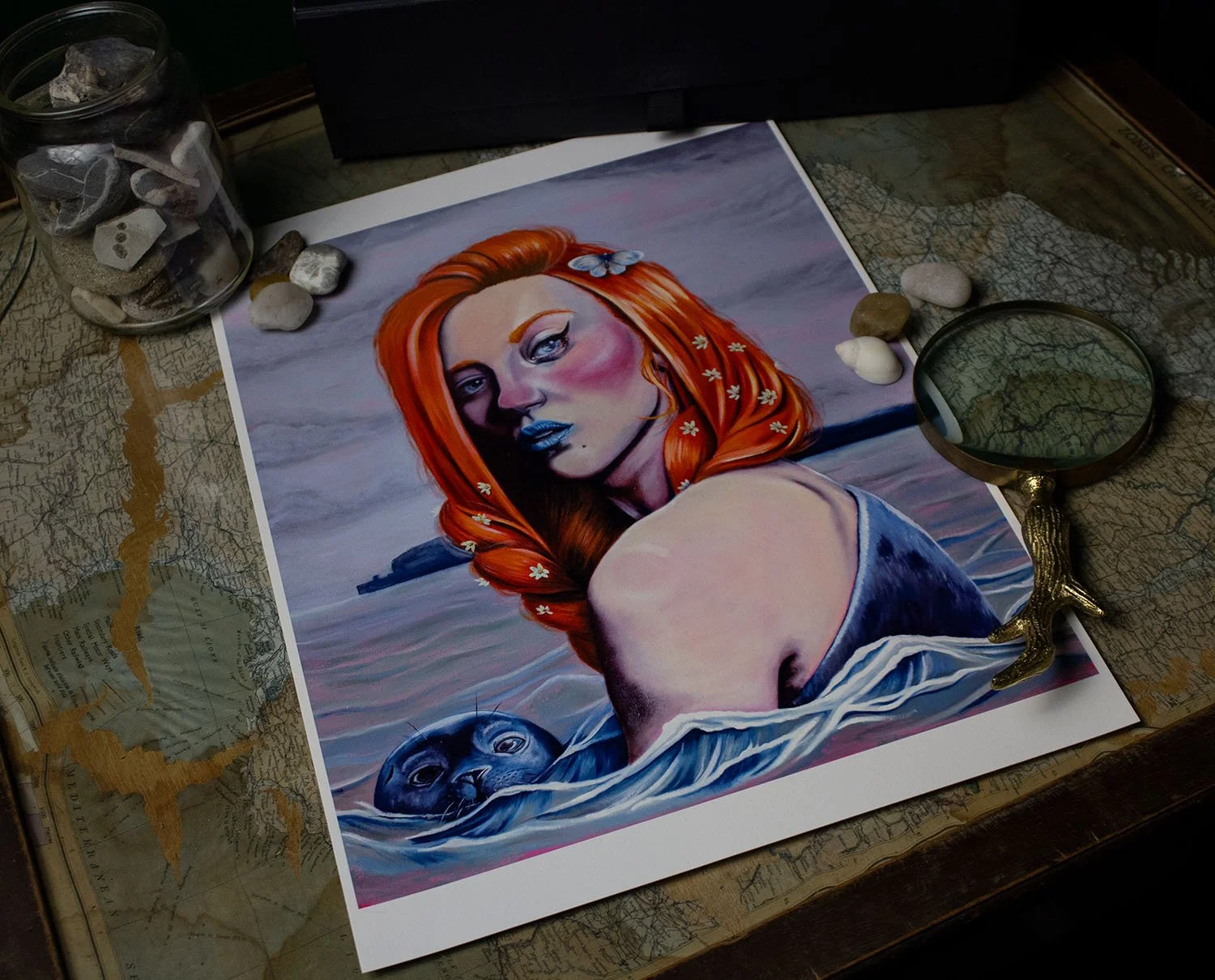 An artistic painting of a woman with red hair and a blue butterfly in her hair, partially submerged in water with a seal nearby, surrounded by rocks and a magnifying glass on an old map.