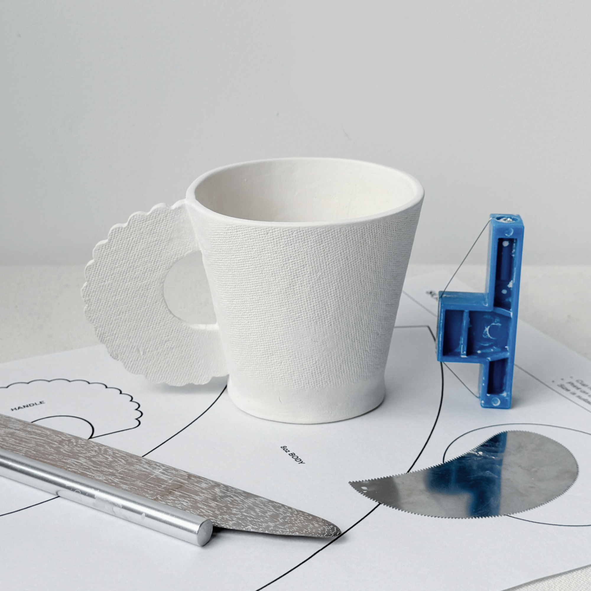 A pottery slab cup conic mug template with a scalloped handle.