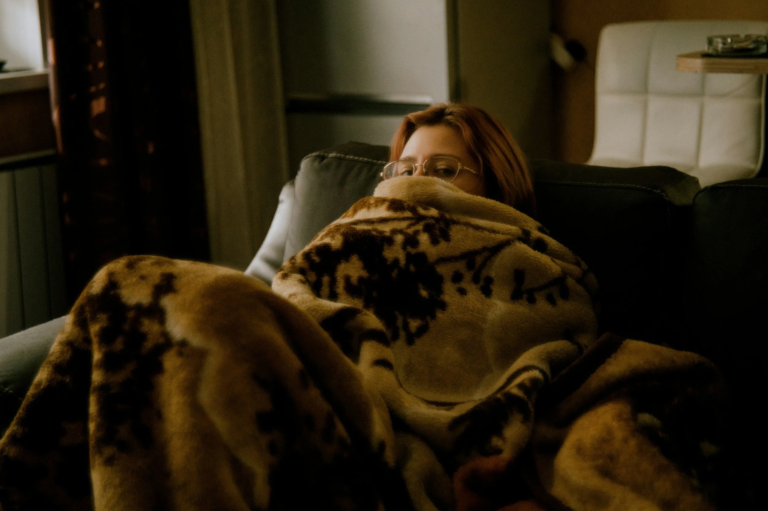 Person resting under a blanket while working from home on a low-capacity day.