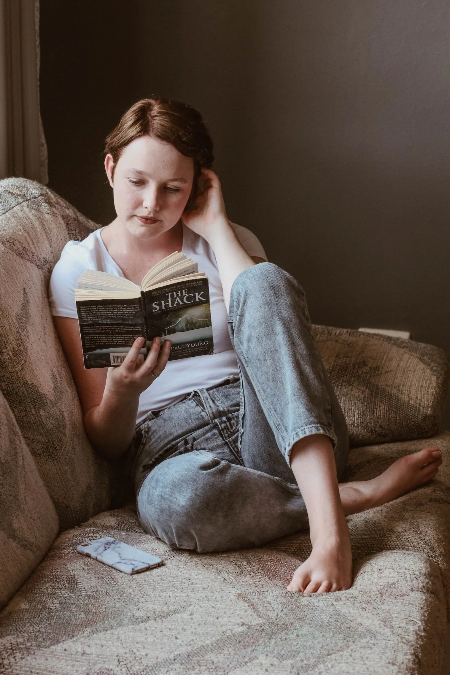 Person relaxing on a couch reading a book, representing downtime and nervous-system recovery