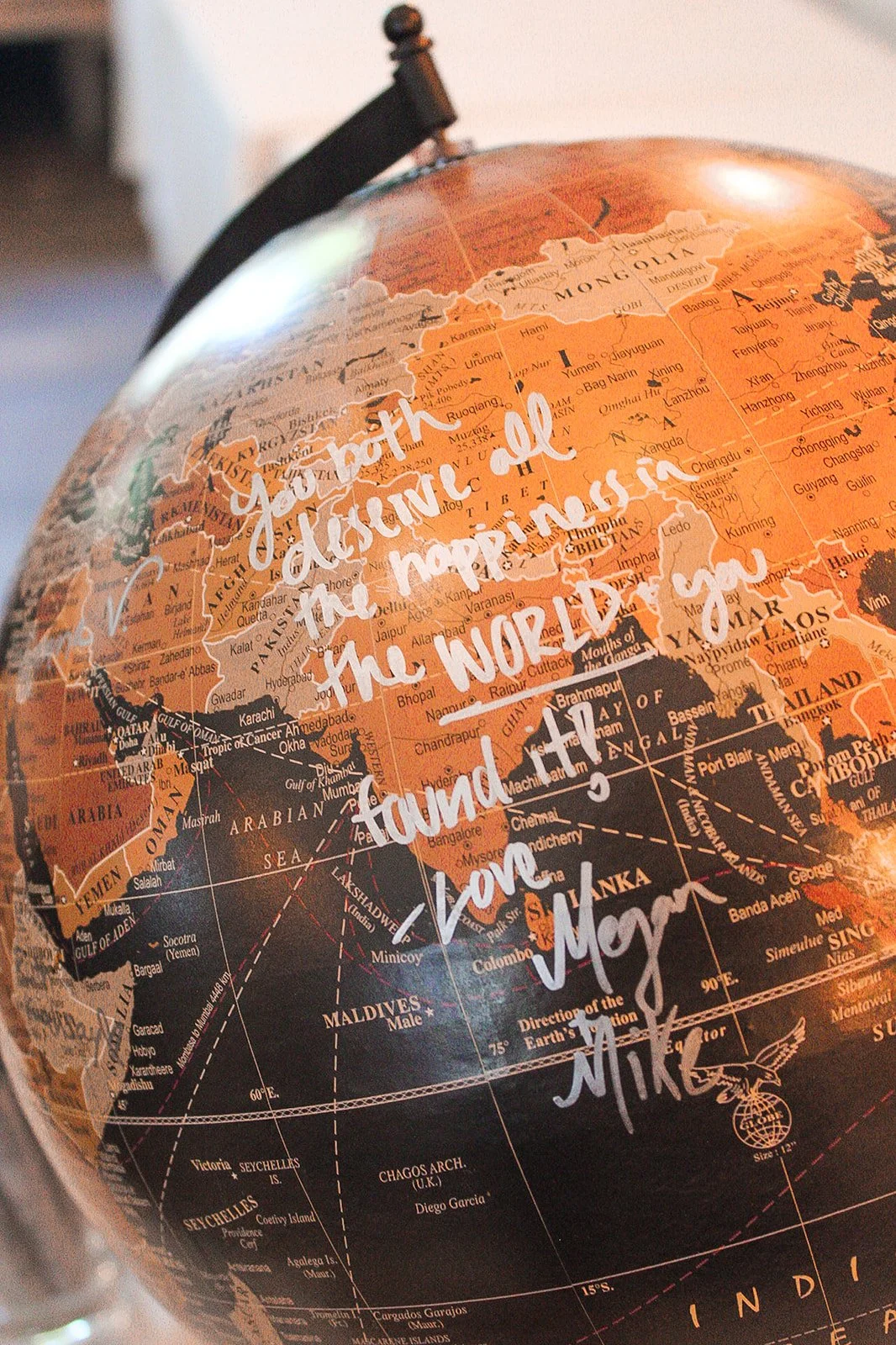A globe with handwritten text overlay that reads, 'You both understand the happiness in the world found in your love.'