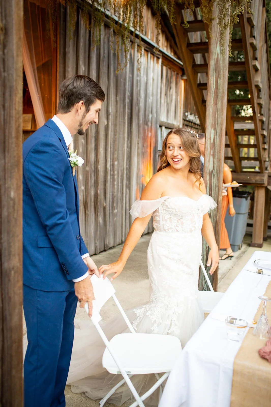 A bride and groom smiling and holding hands during their wedding reception outside.