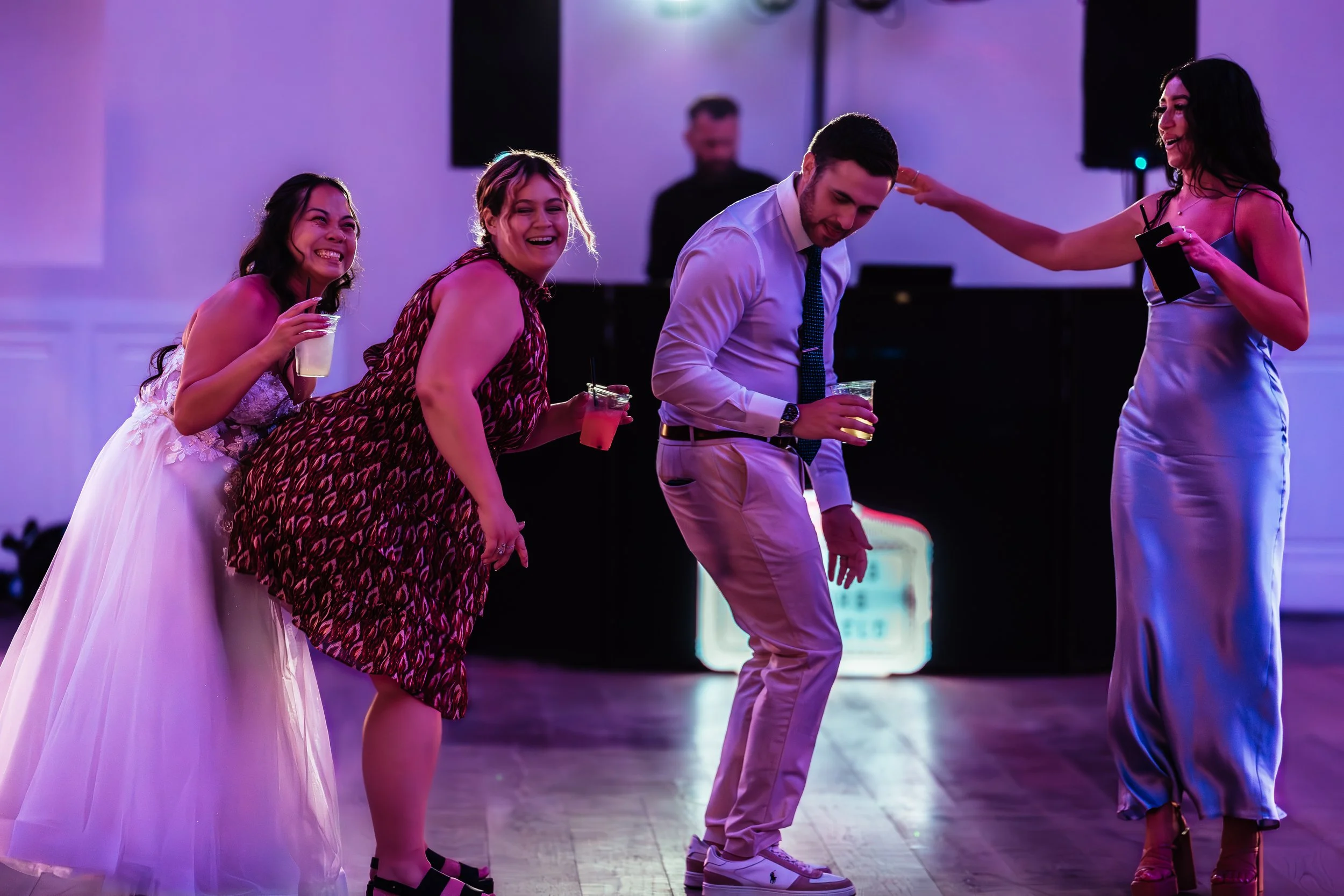 People dancing and enjoying drinks at a celebration or party, with a DJ or music setup in the background. western wedding photographer az rustic wedding photographer az barn wedding photographer az backyard wedding photographer az