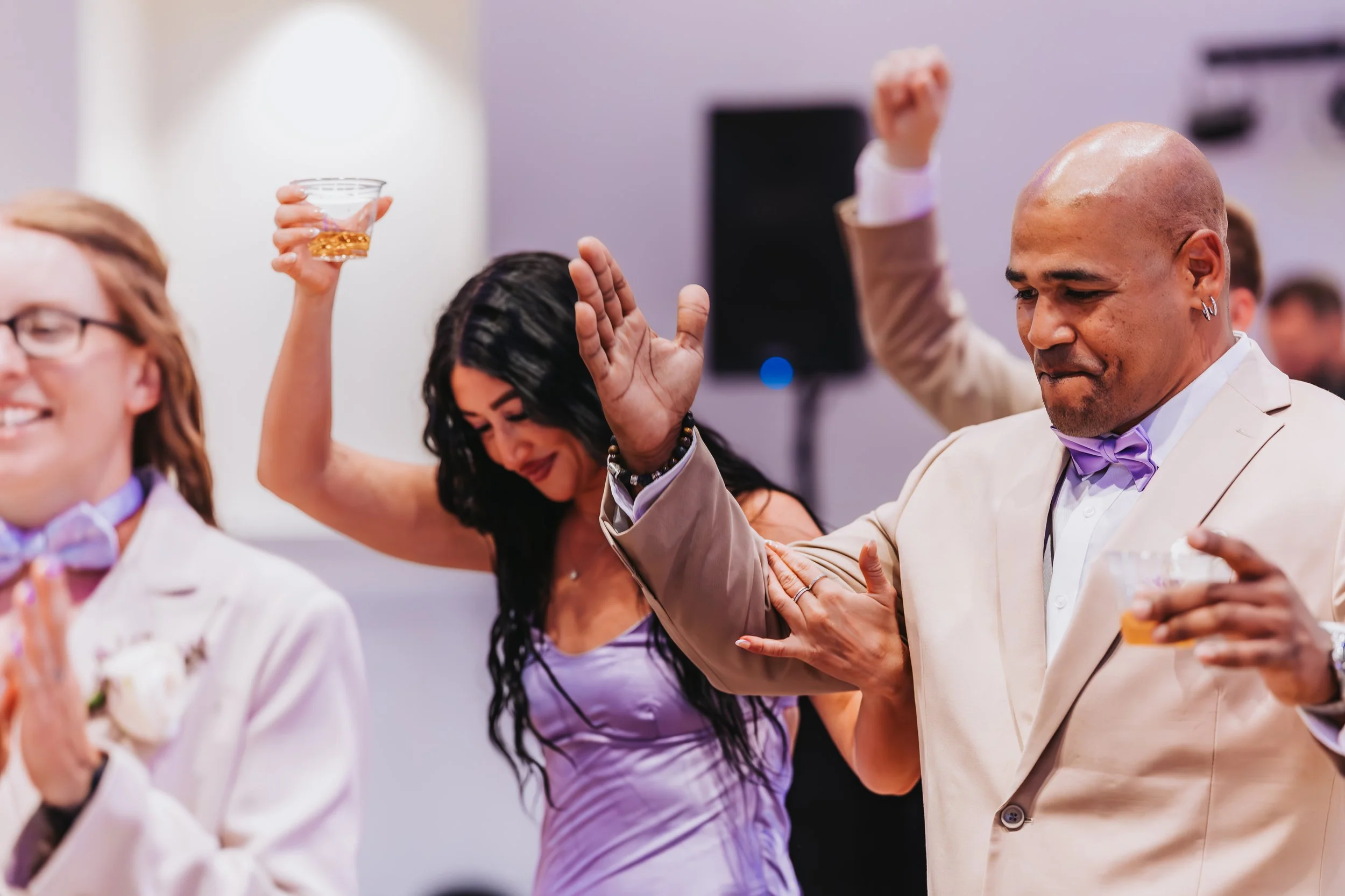People dancing at a celebration, holding drinks, and dressed in formal attire, including suits with bow ties. engagement wedding photographer phoenix az engagement photographer az traveling wedding photographer az