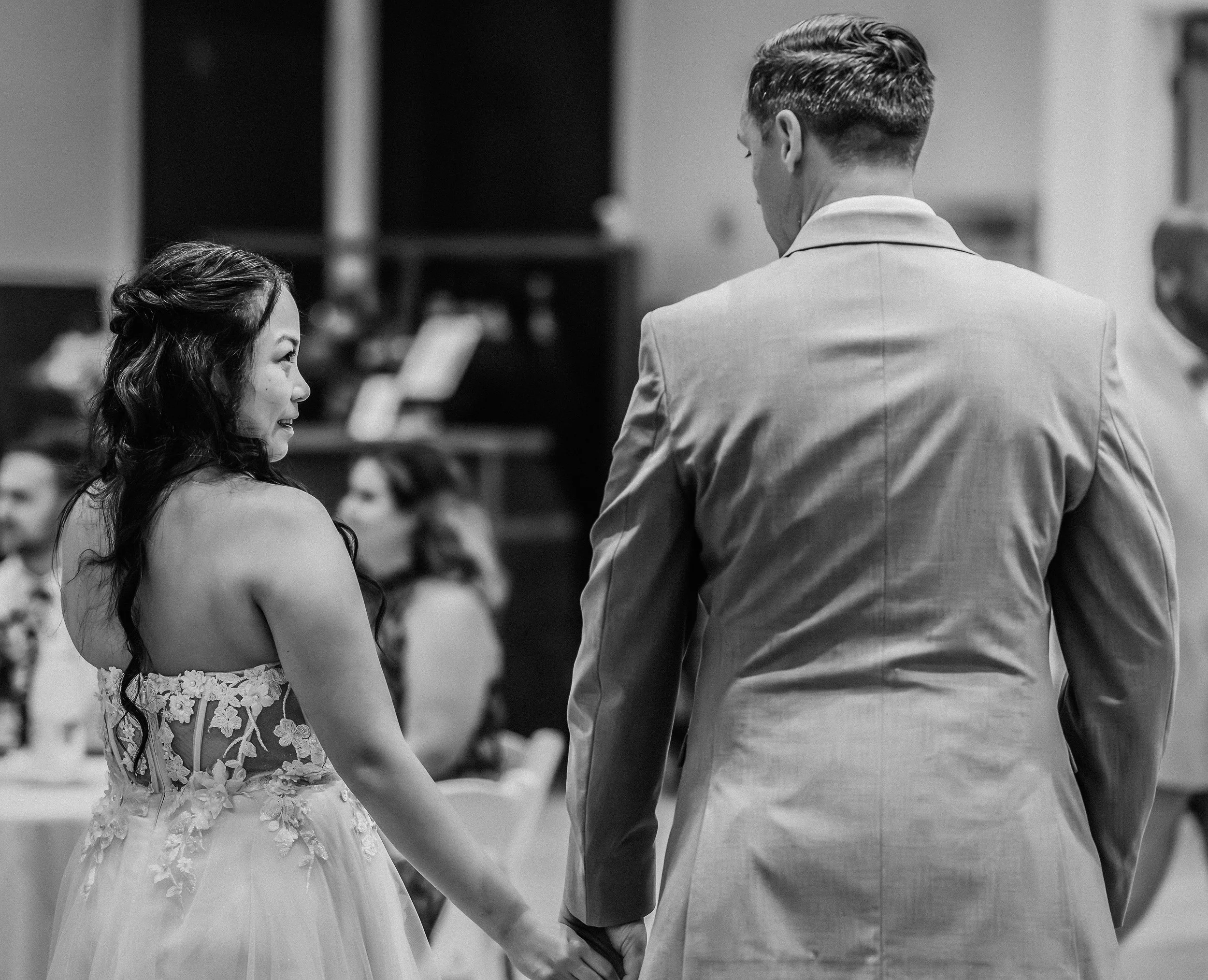 A bride and groom holding hands during their wedding reception in a black and white photo. western wedding photographer az rustic wedding photographer az barn wedding photographer az backyard wedding photographer az