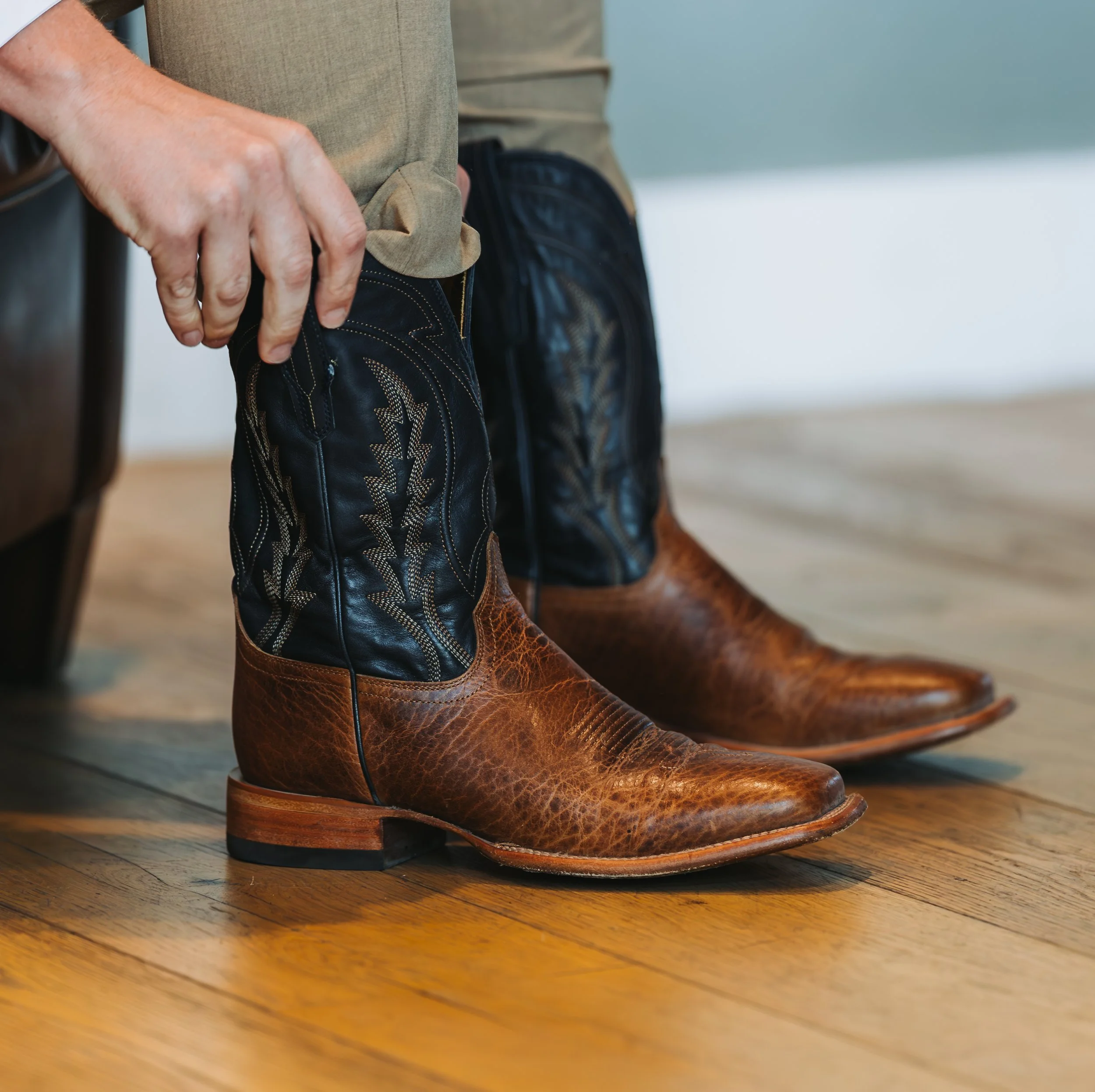 A person wearing cowboy boots and leather chaps sitting on a wooden floor. wedding photographer Prescott az flagstaff az wedding photographer wedding photographer northern az