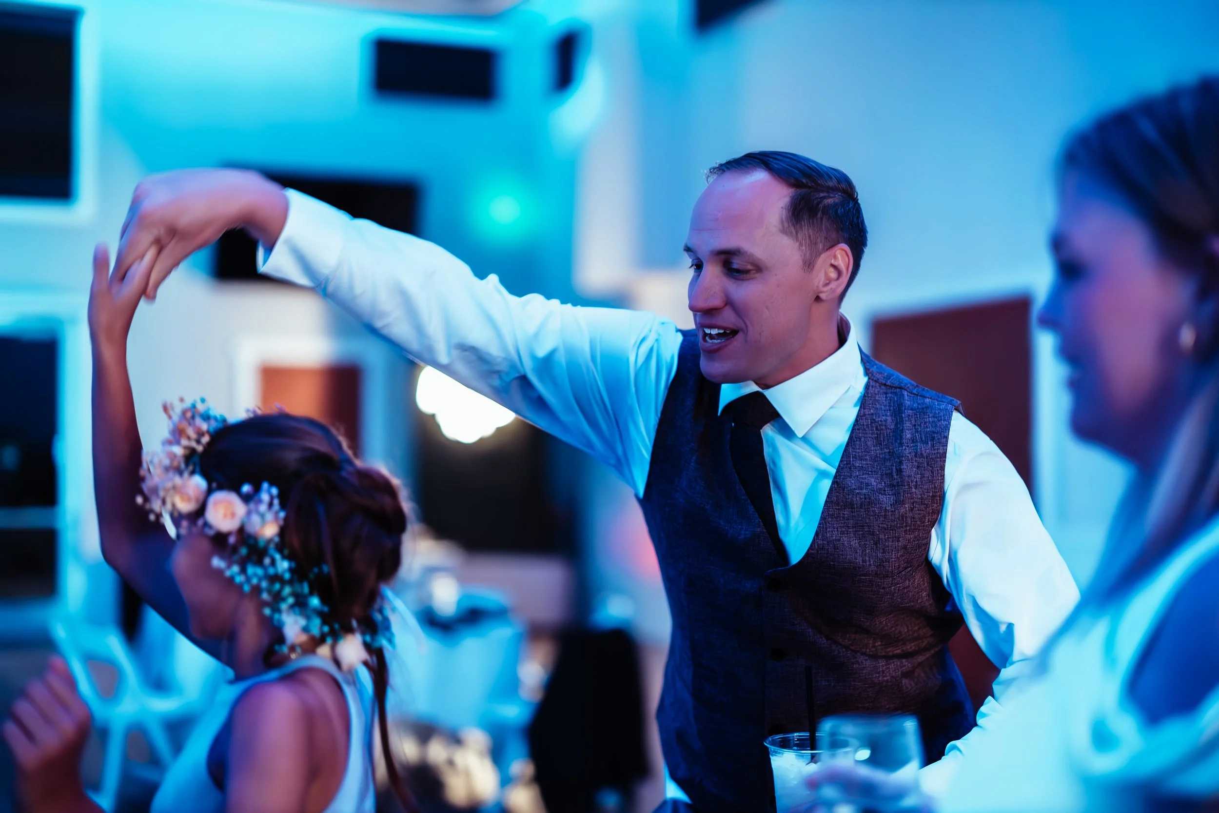 A man in a vest and tie dancing with a young girl with flowers in her hair at a party or wedding reception. western wedding photographer az rustic wedding photographer az barn wedding photographer az backyard wedding photographer az