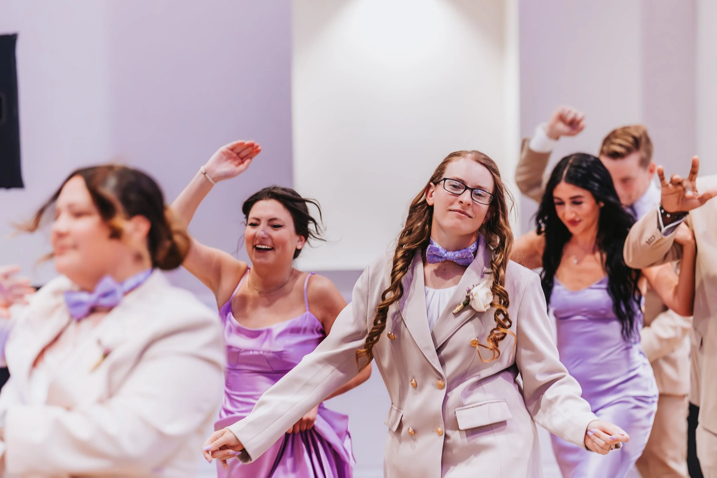 People dancing at a wedding celebration, dressed in formal wear with lavender dresses and light-colored suits. engagement wedding photographer phoenix az engagement photographer az traveling wedding photographer az