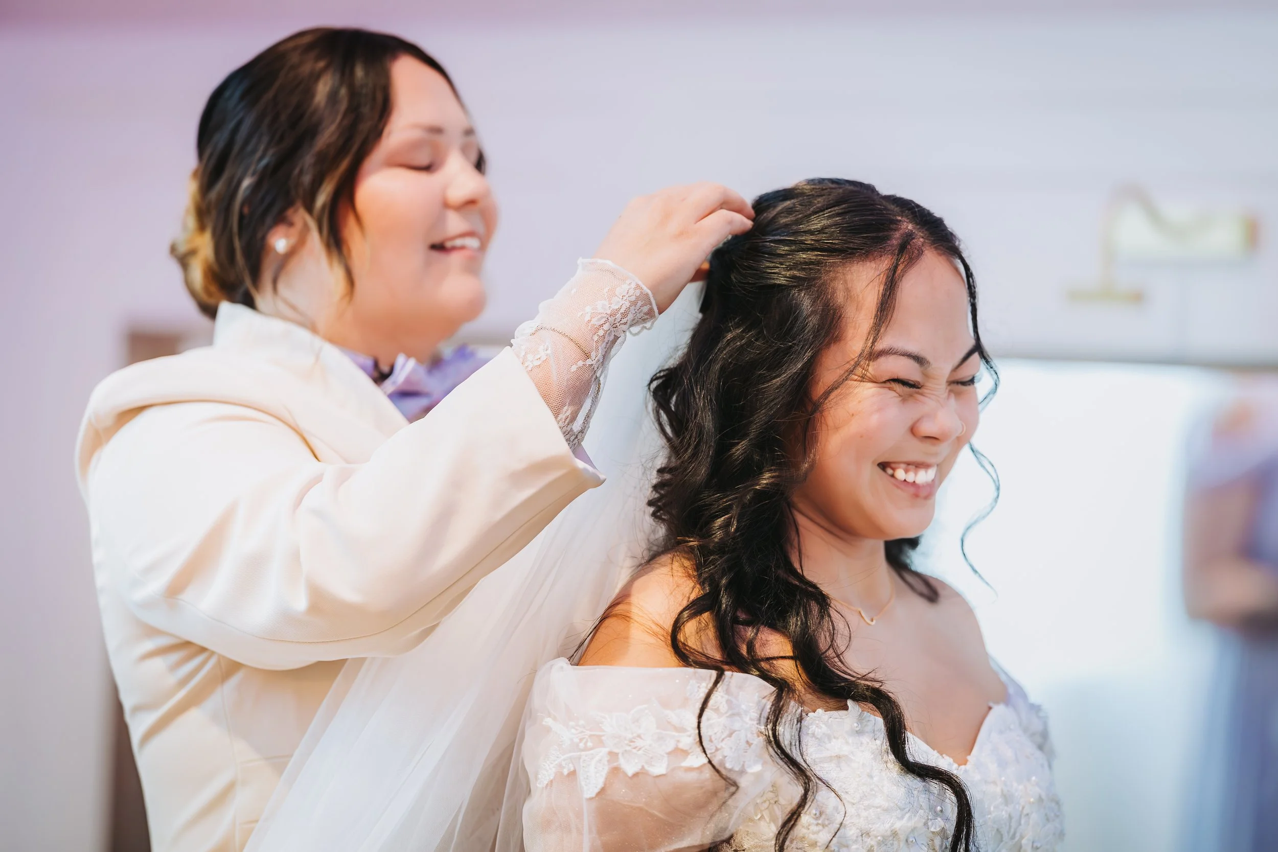 A woman in a wedding dress smiling while another woman, possibly a stylist, helps her with her hair. traveling wedding photographer az wedding photographer Prescott az wedding photographer flagstaff az
