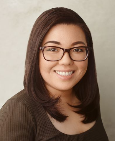 A woman with shoulder-length brown hair and glasses smiling at the camera.