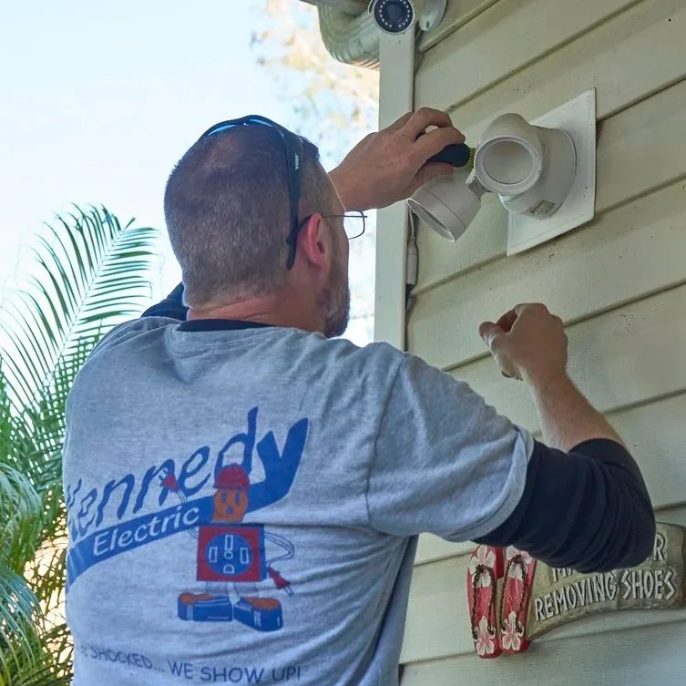 Technician mounting outdoor light fixture on siding, supporting safer electrical planning and clearer breaker identification for reliable home power management.