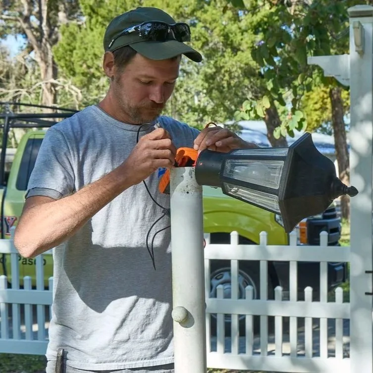 Technician adjusting exterior motion sensor fixture demonstrating proper installation and troubleshooting for reliable outdoor security lighting performance.