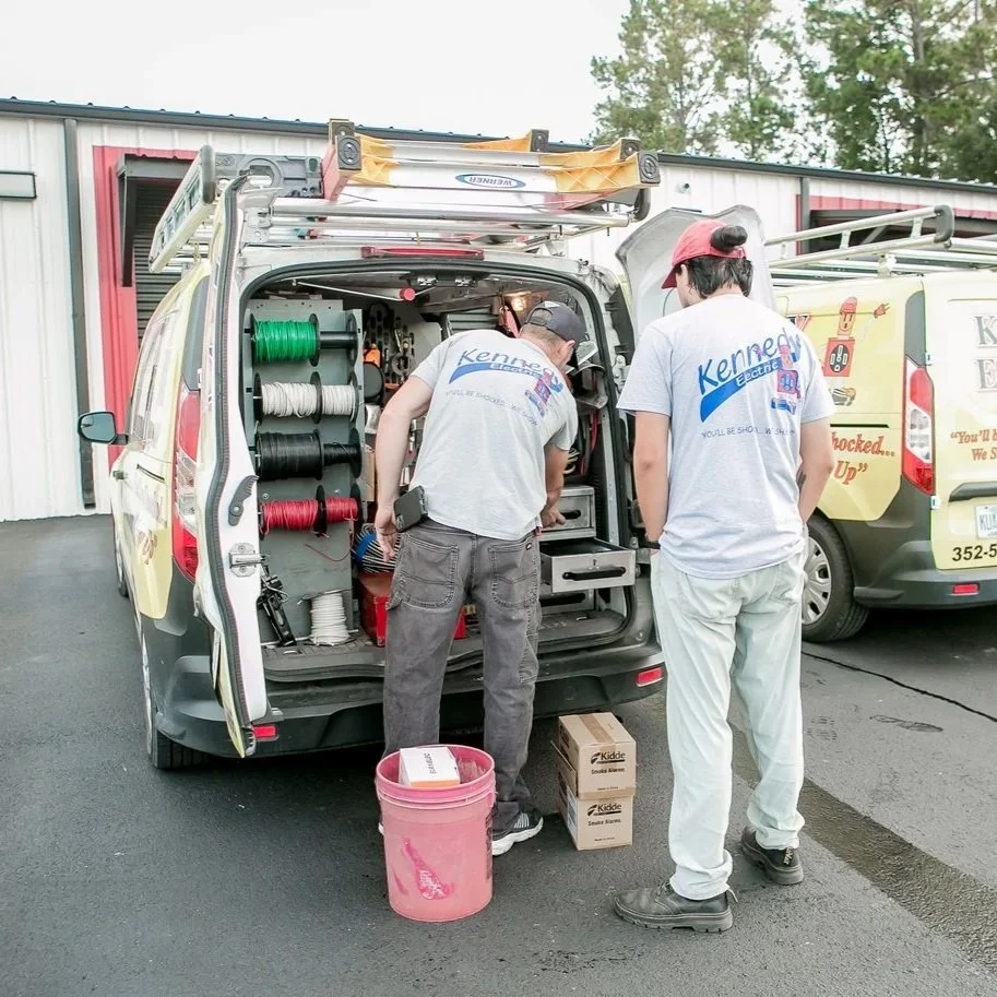 Electricians reviewing tools inside Kennedy Electric van, representing proactive storm preparation and dependable residential backup power services.