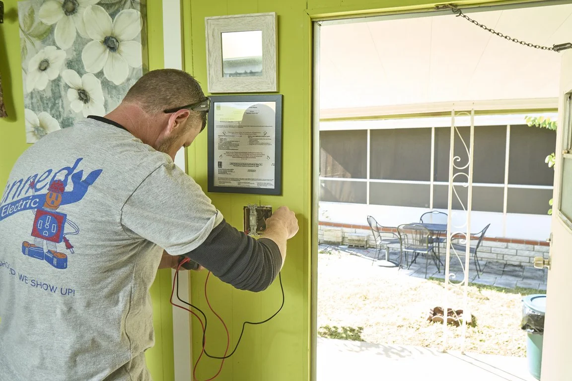 Licensed electrician inspecting interior outlet wiring with testing tools near doorway, focusing on tamper resistant installation and family electrical safety.