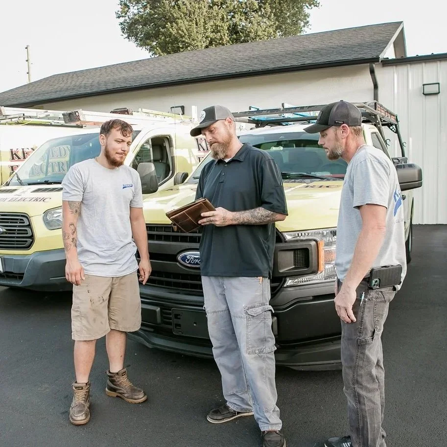 Electricians standing near work trucks evaluating generator options and electrical planning for reliable residential backup power installation.