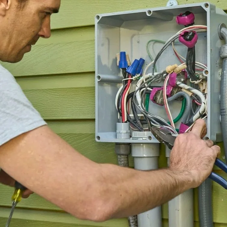 Professional electrician working on outdoor electrical panel wiring, focusing on NEC standards, moisture protection, and safe home electrical installation.