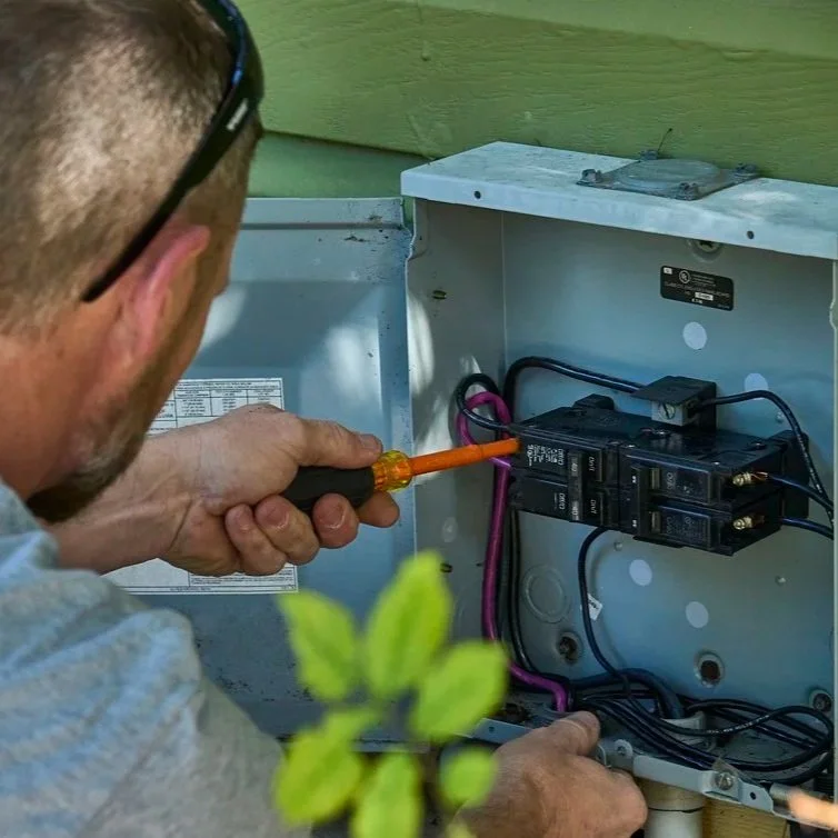 Technician checking home breaker panel and wiring while investigating overheating circuits, loose connections, and potential burnt electrical wire hazards inside.
