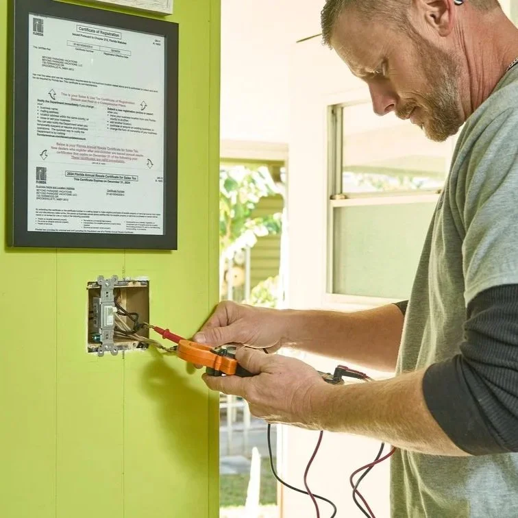 Professional electrician testing exposed outlet wiring with meter tools, focusing on safe installation and improved electrical protection inside homes.