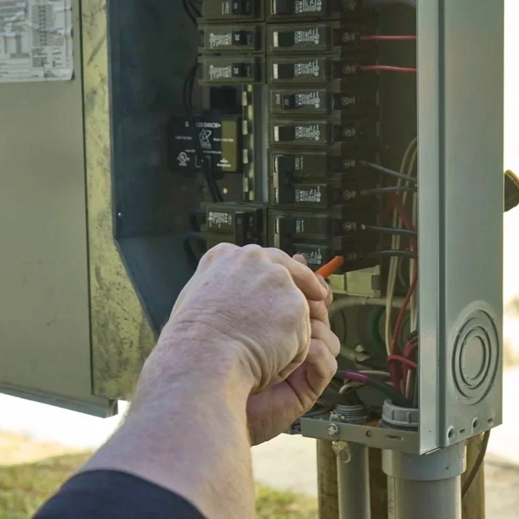 Technician checking recessed light housing near insulation showing safe lighting installation and difference between IC-rated and non-IC fixtures.