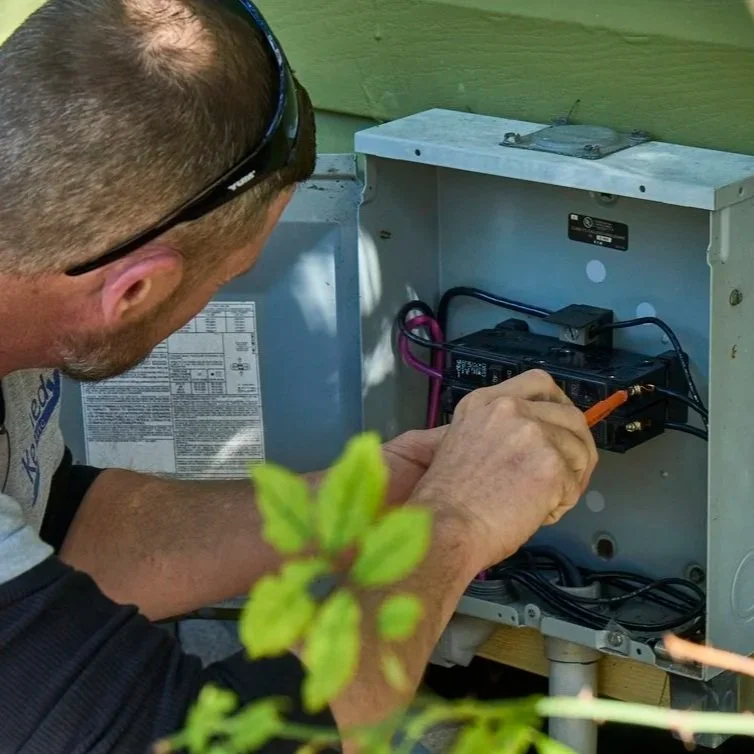 Technician wiring GFCI outlet in exterior junction box, identifying line and load connections for correct downstream electrical protection.