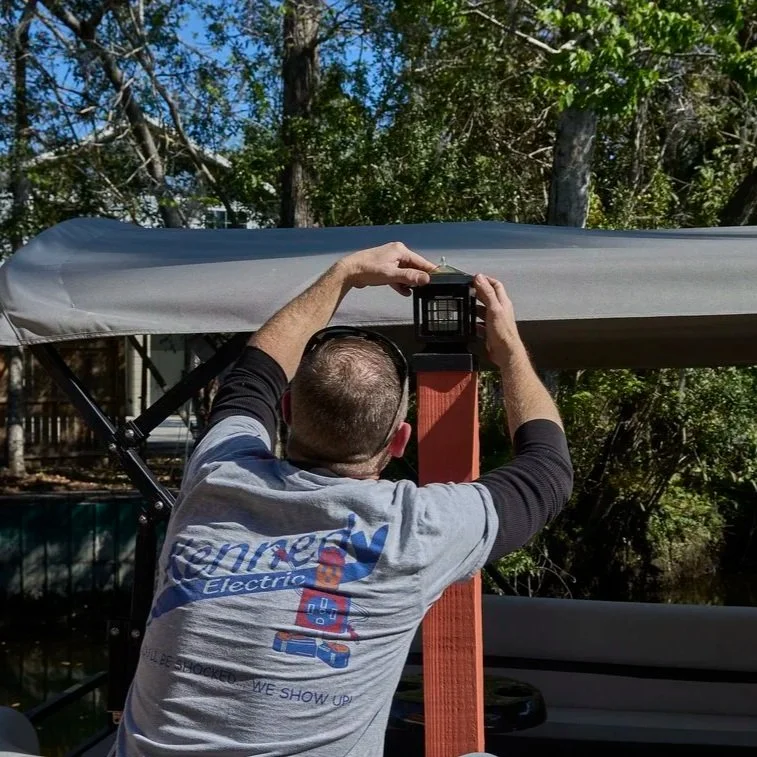 Technician mounting outdoor light fixture on deck post, representing electrical inspection and repair after water intrusion in residential wiring.