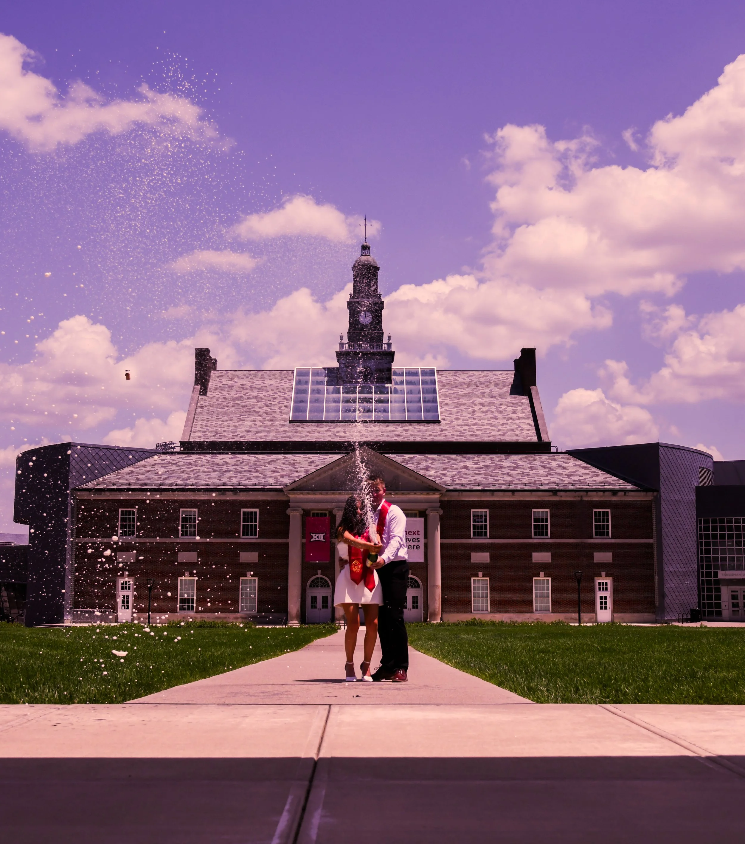 Couple celebrating on campus with campus building and clock tower in background
